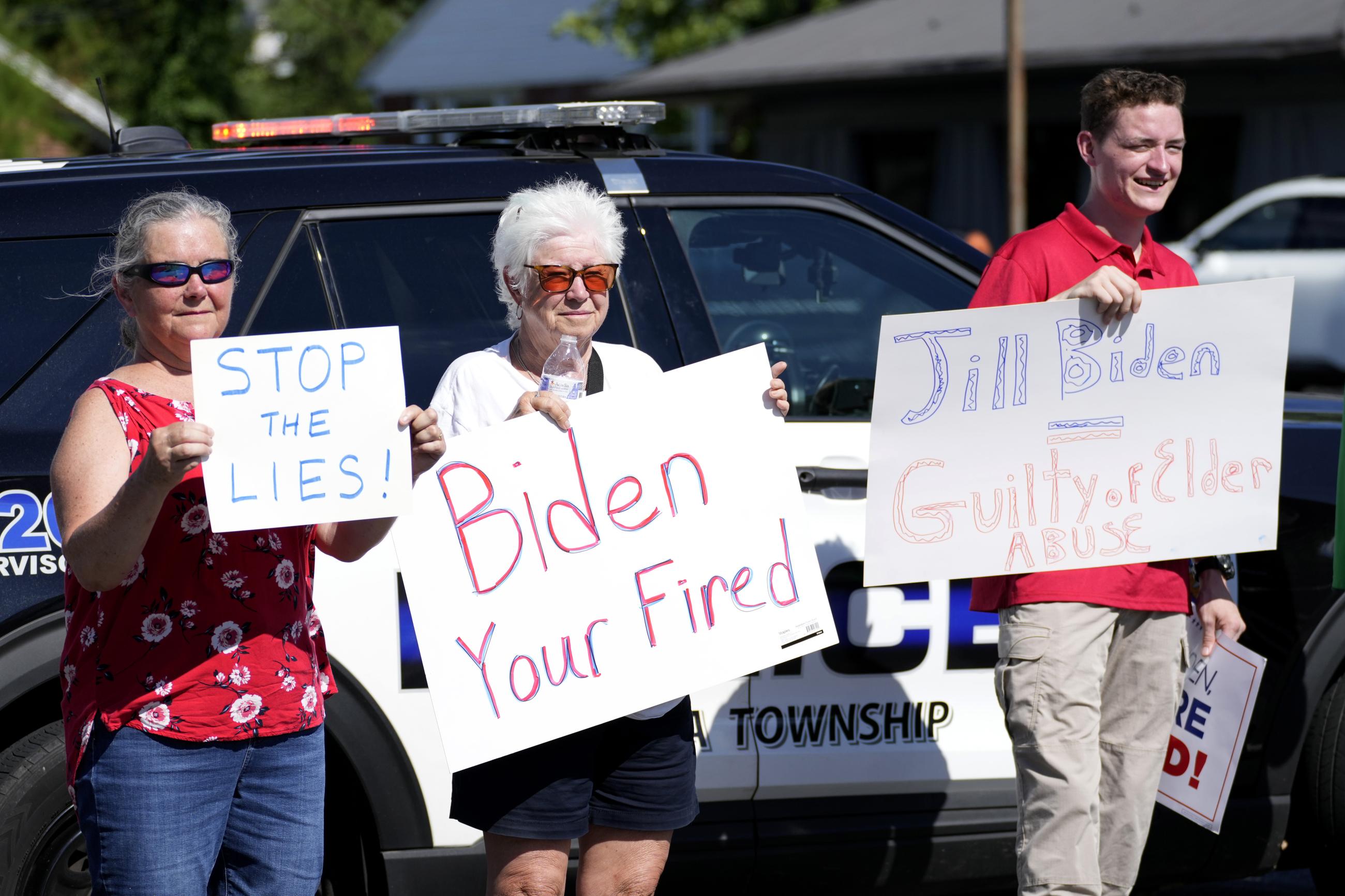 Protesters carrying signs in Harrisburg, Pennsylvania, as President Biden attended a campaign event on July 7. (AP Photo/Stephanie Scarbrough)