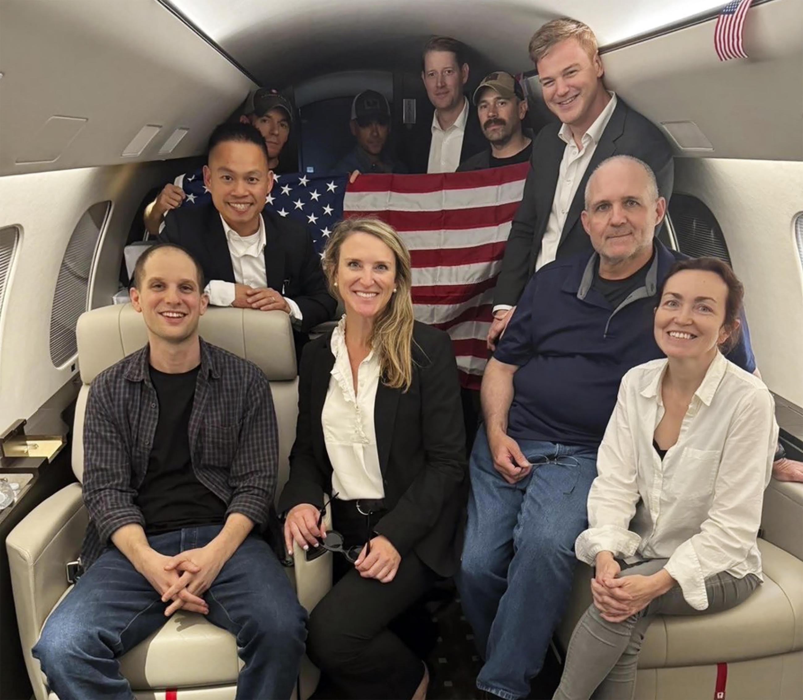 This image released by the White House shows Evan Gershkovich (left), Alsu Kurmasheva (right), Paul Whelan (second from right), and others aboard a plane following their release from Russian captivity on Thursday. (White House via AP)