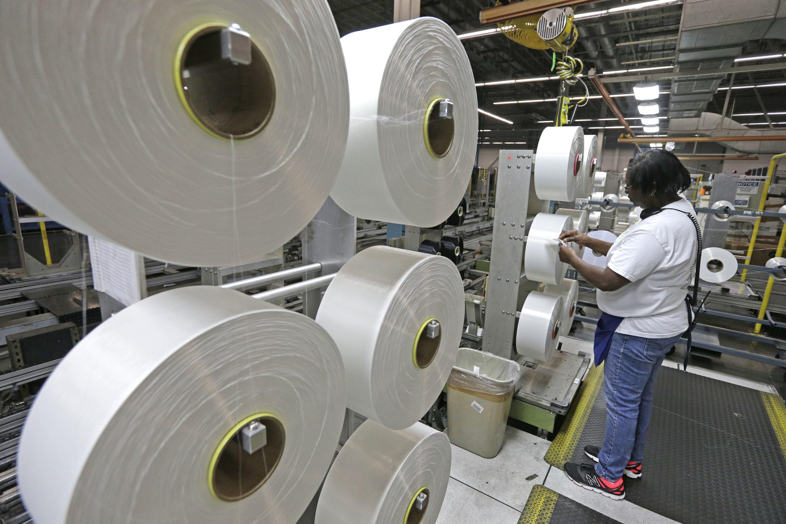 A worker examines a spool of thread made from recycled plastic bottles. (AP Photo/Chuck Burton, File)
