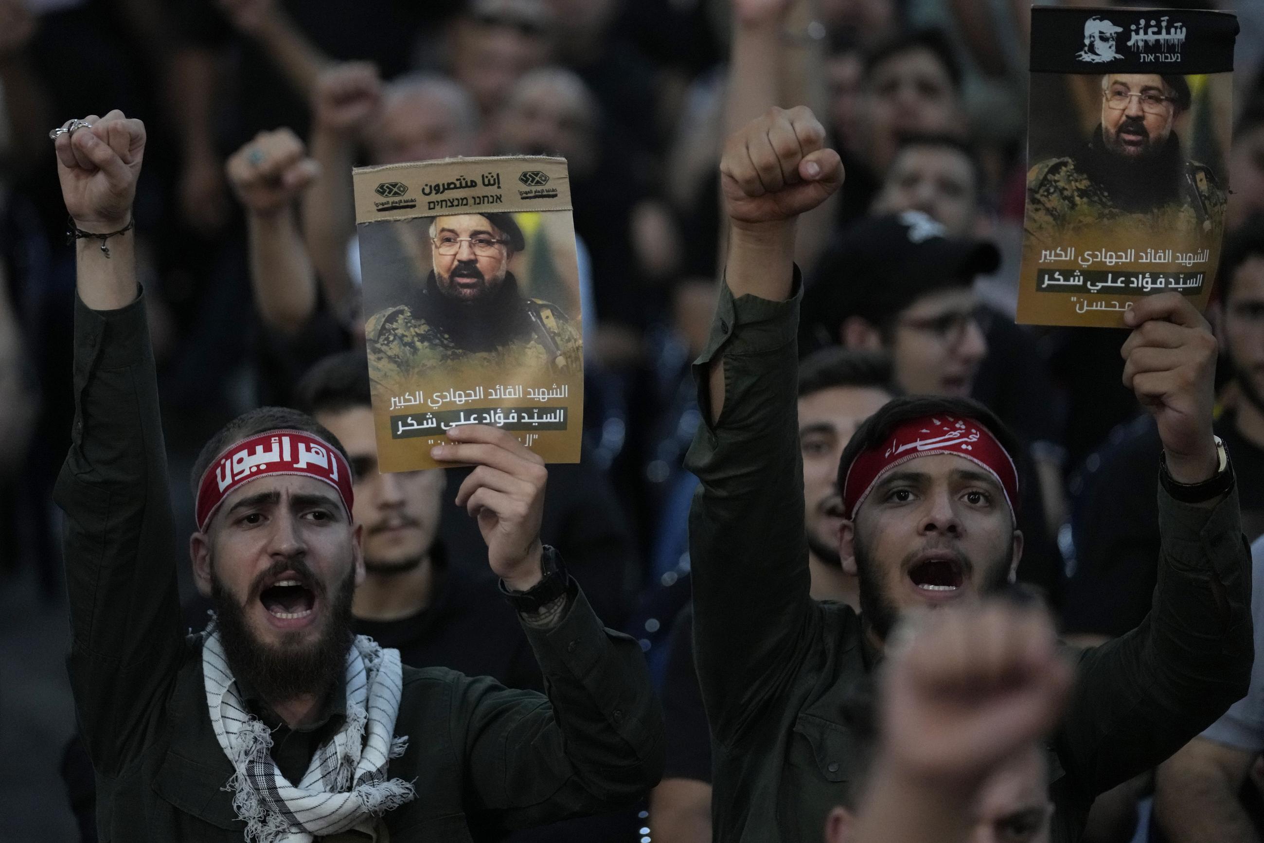 Hezbollah supporters shout slogans and hold up portraits that show the top commander Fouad Shukur, who was killed by an Israeli airstrike last week, during his funeral procession late last week in a southern suburb of Beirut, Lebanon. (AP Photo/Hussein Malla, File)
