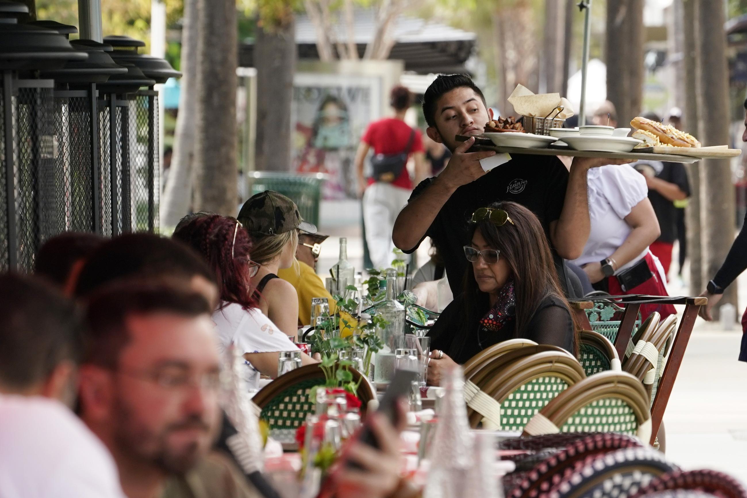 A waiter delivers food to patrons at a restaurant, Jan. 21, 2022, in Miami Beach, Florida. (AP Photo/Marta Lavandier, File)