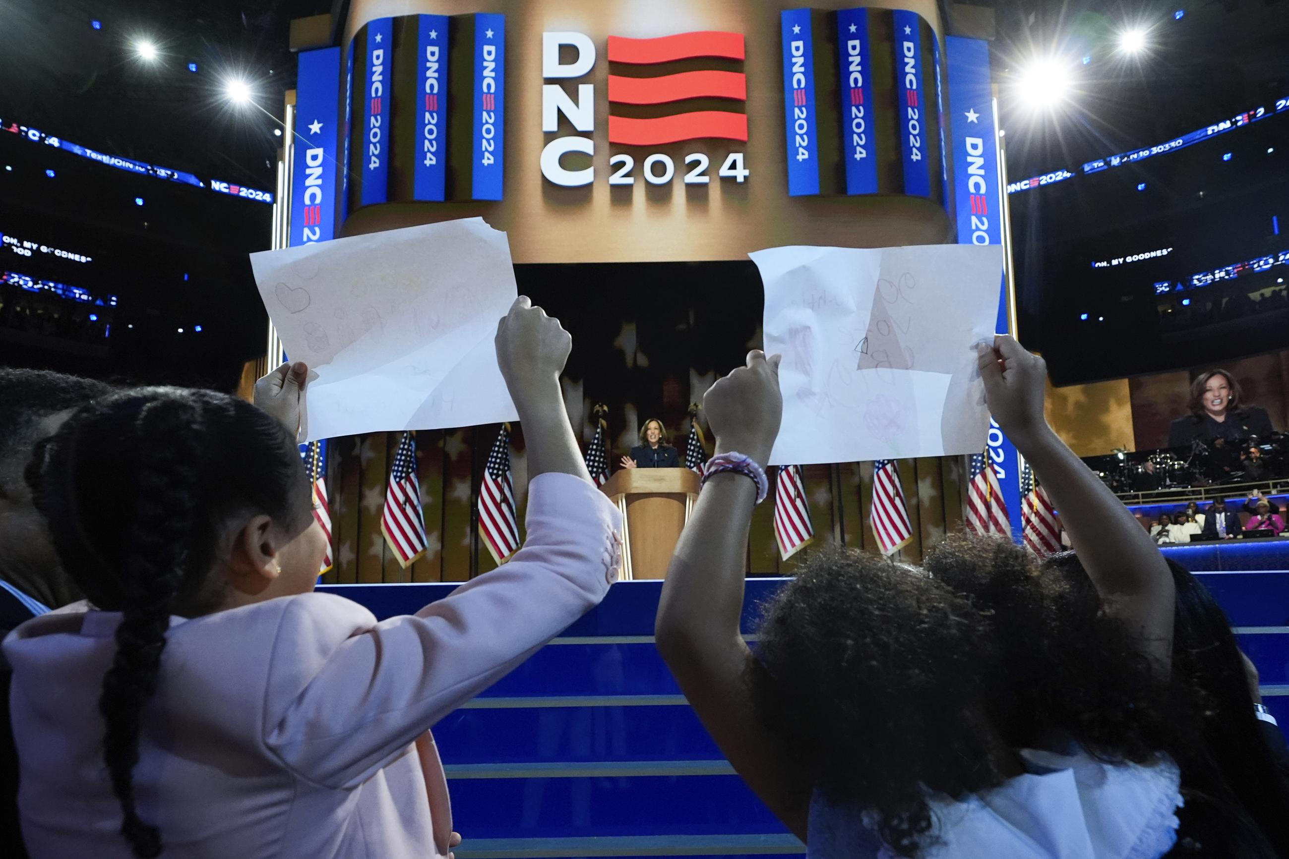 Vice President Kamala Harris speaks as her grand-nieces Amara and Leela Ajagu hold signs at the Democratic National Convention in Chicago on Aug. 22. (AP Photo/Paul Sancya)