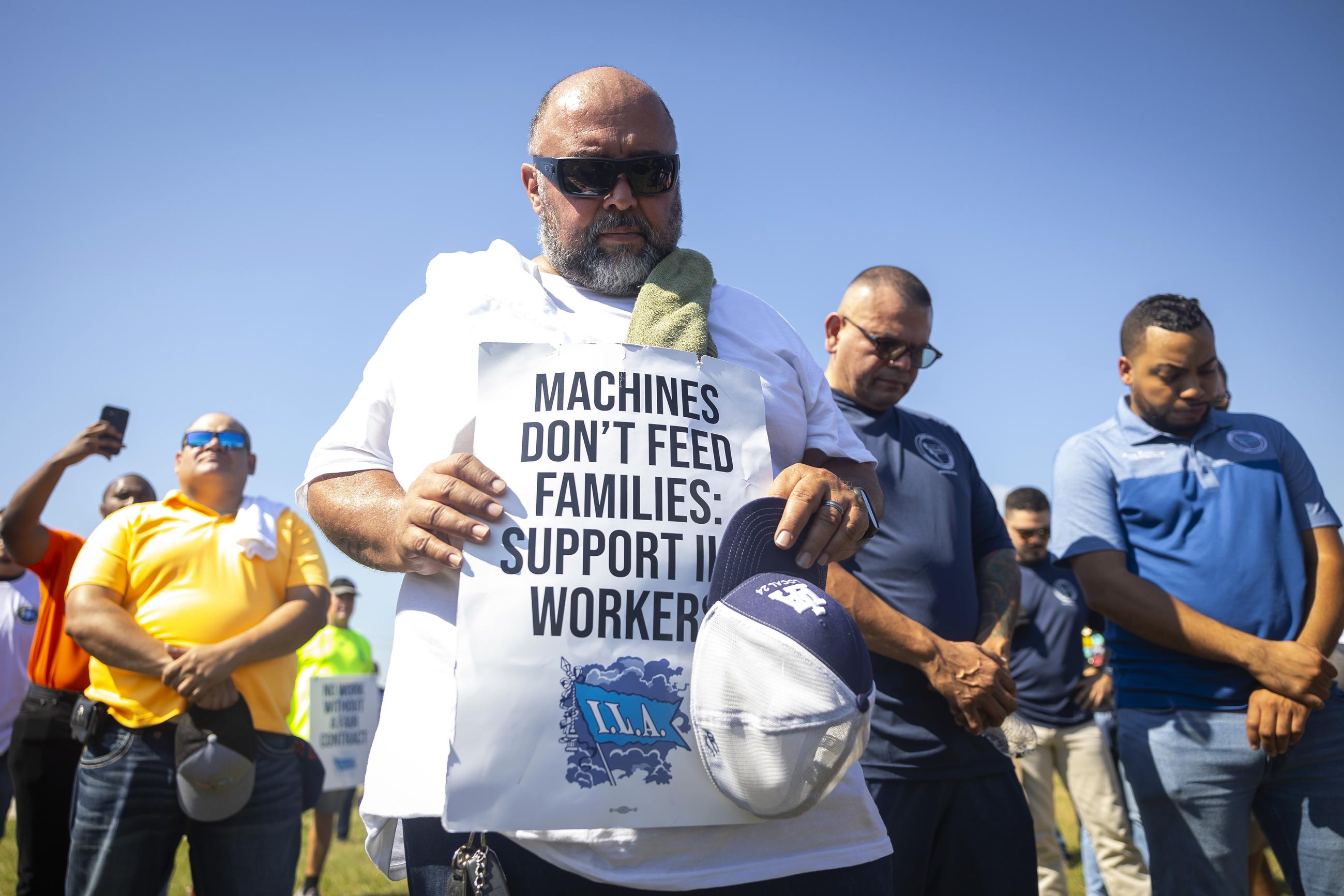 Longshoremen bow for a prayer during a strike at the Bayport Container Terminal in Houston on Oct. 1. (AP Photo/Annie Mulligan)