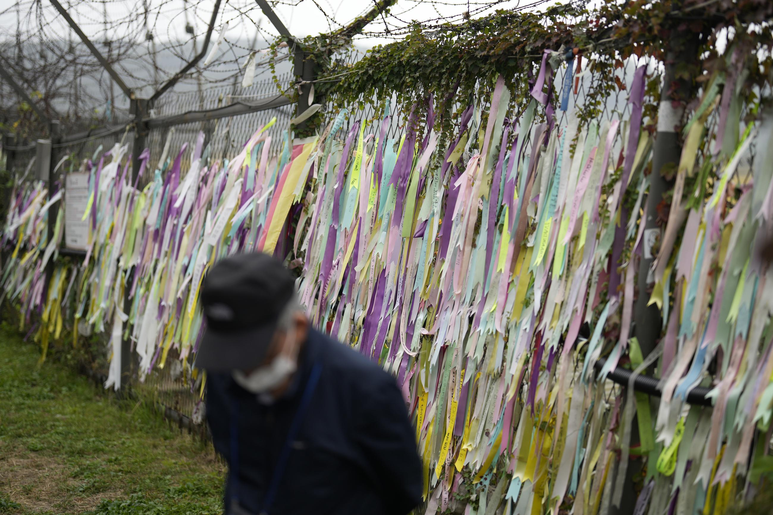 A visitor walks near a wire fence decorated with ribbons written with messages wishing for the reunification of the two Koreas at the Imjingak Pavilion in Paju, South Korea, Tuesday. (AP Photo/Lee Jin-man)