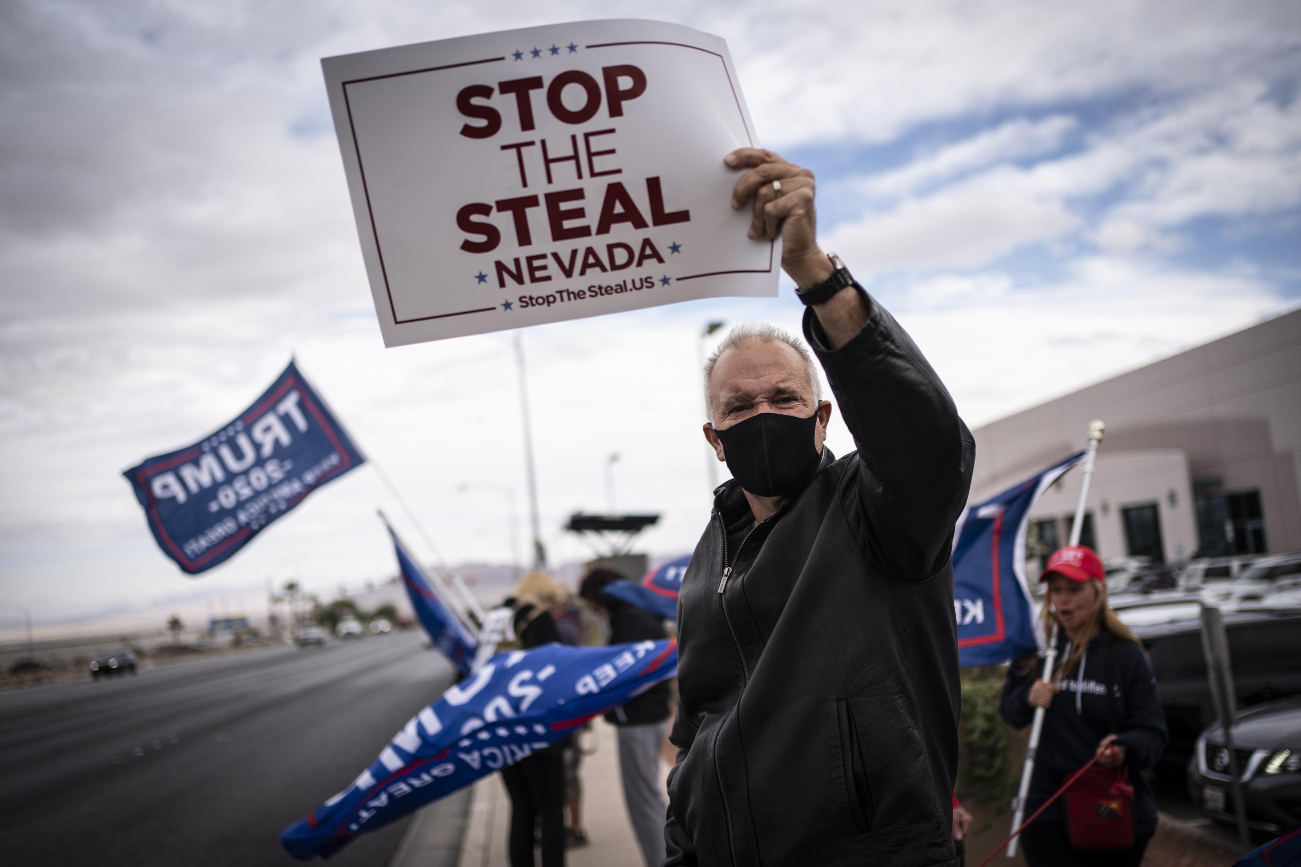 Supporters of then-President Trump hold signs as they stand outside of the Clark County Elections Department in North Las Vegas on Nov. 7, 2020. (AP Photo/Wong Maye-E, File)
