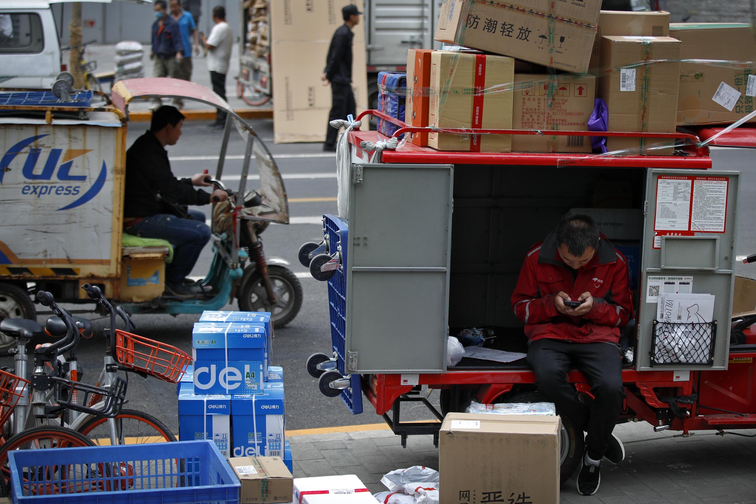 A private delivery company's courier sits on his delivery cart sorting boxes of goods for his customers outside an office building at the Central Business District in Beijing. (AP Photo/Andy Wong)