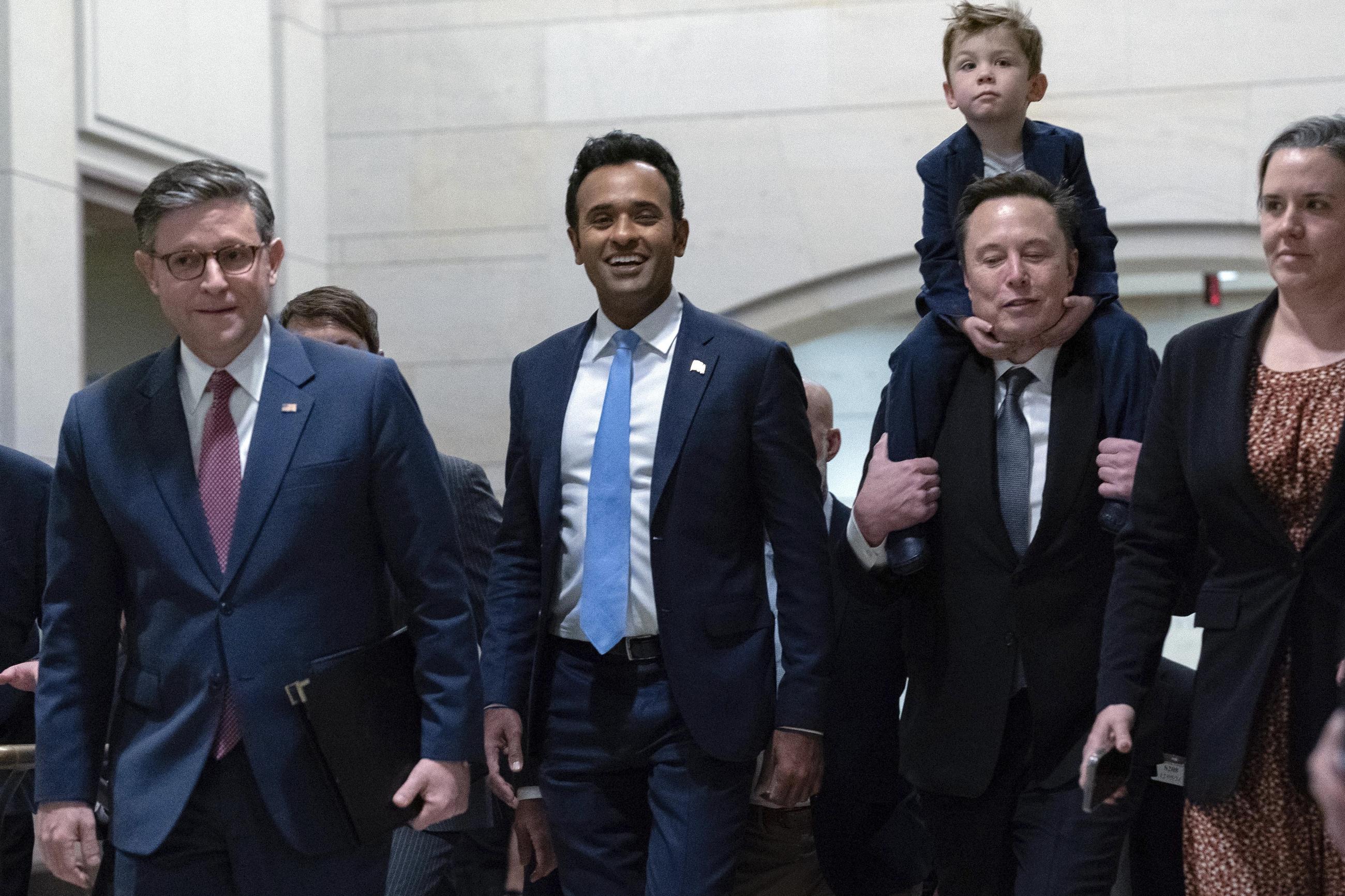 House Speaker Mike Johnson walks with Vivek Ramaswamy and Elon Musk, who is carrying his son X Æ A-Xii, as they walk to a meeting to discuss President-elect Trump's planned Department of Government Efficiency on Capitol Hill Thursday. (AP Photo/Jose Luis Magana)
