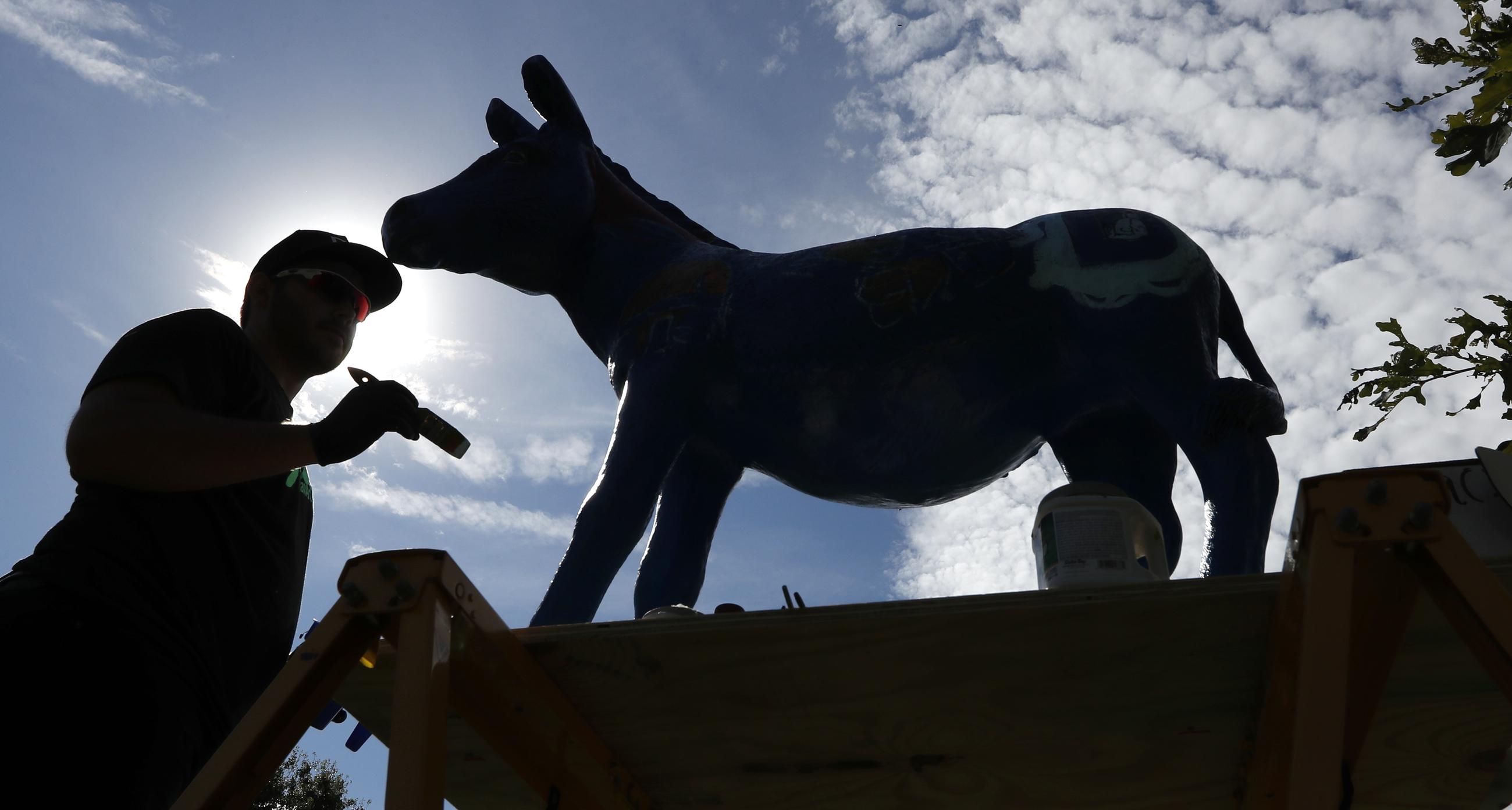 Ben Schuh, of Des Moines, Iowa, paints Daisy the Donkey during the Polk County Democrats Steak Fry, Saturday, Sept. 30, 2017, in Des Moines, Iowa. (AP Photo/Charlie Neibergall)