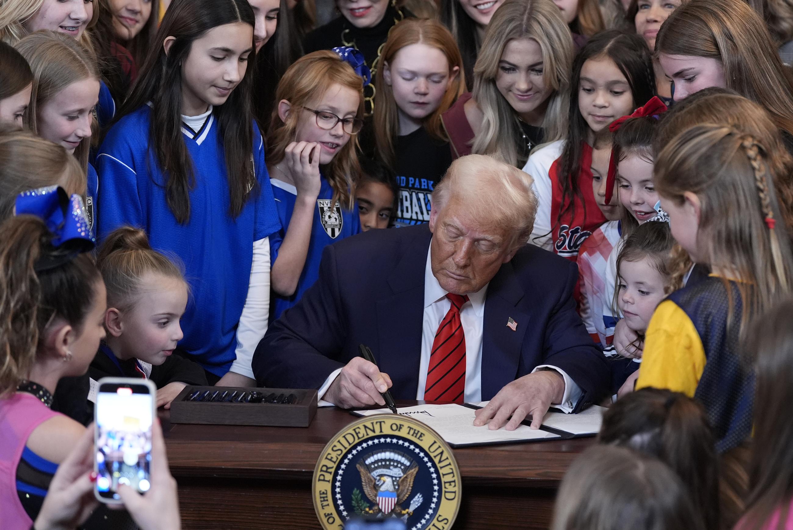 President Trump signs an executive order barring transgender female athletes from competing in women's or girls' sporting events, in the East Room of the White House on Feb. 5. (AP Photo/Alex Brandon)