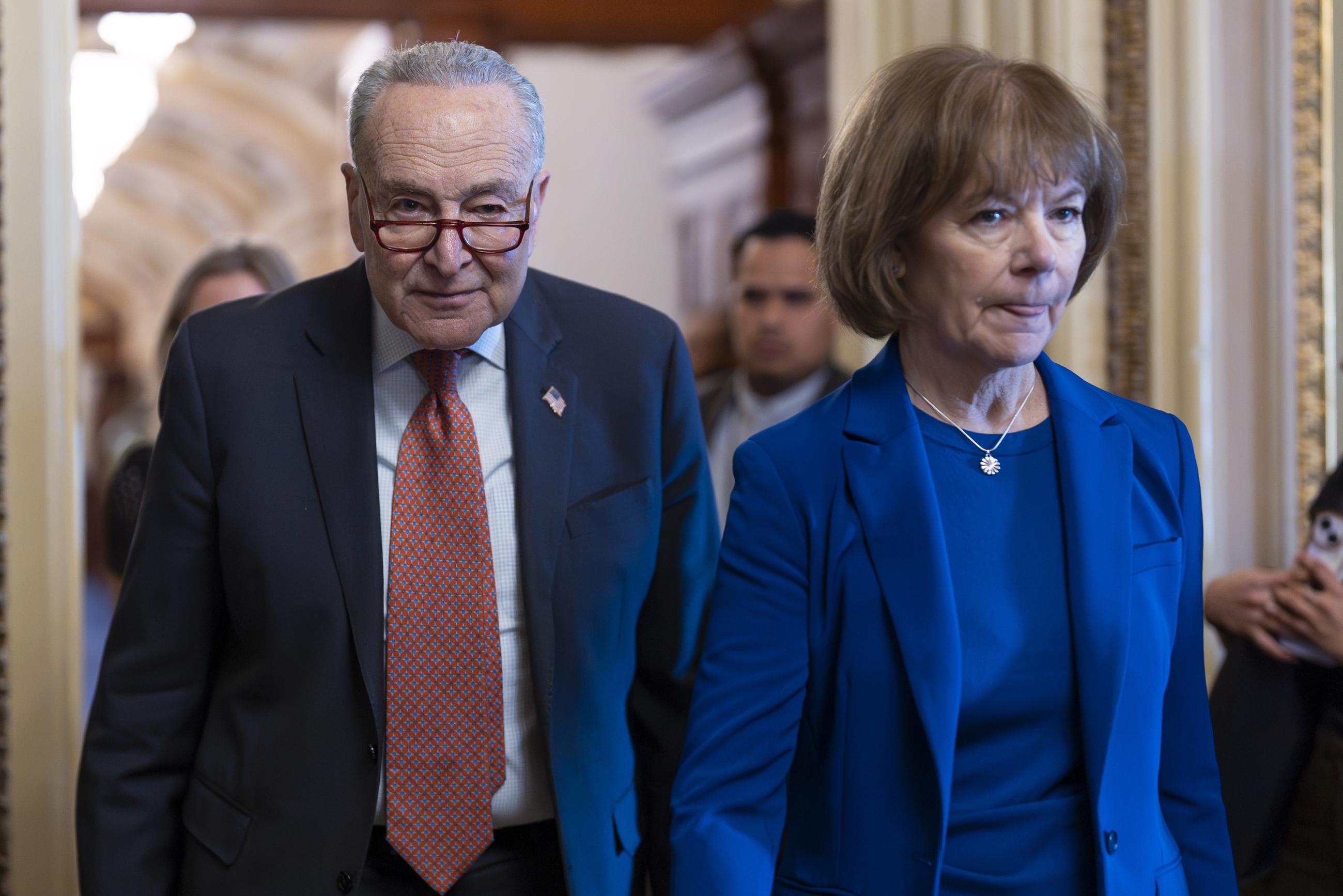 Senate Minority Leader Chuck Schumer walks with Sen. Tina Smith as Democrats gather behind closed doors to mount a last-ditch protest over a Republican-led, House-passed spending bill Thursday. (AP Photo/J. Scott Applewhite)