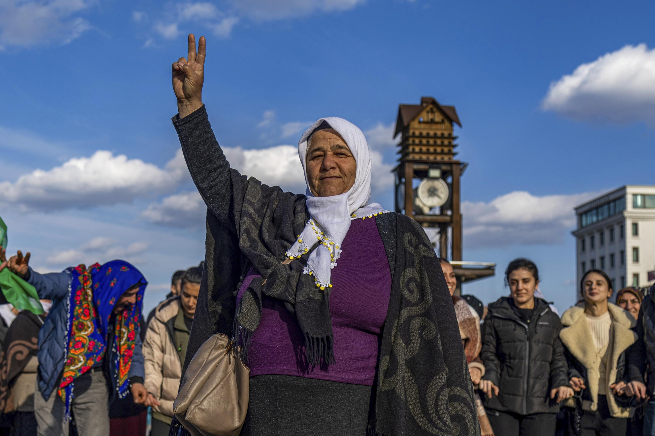 A Kurdish woman shows the V-sign as she gathers with others to watch live on a TV screen a Pro-Kurdish Peoples' Equality and Democracy Party delegation releasing a statement from the jailed leader of the rebel Kurdistan Workers' Party, or PKK, Abdullah Öcalan, in Diyarbakir, Turkey, in February. (AP Photo/Metin Yoksu)