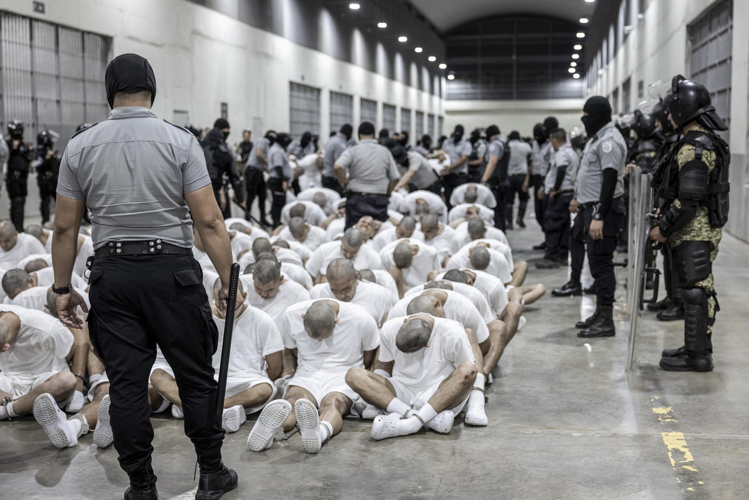 A prison guard transfers deportees from the U.S., alleged to be Venezuelan gang members, to the Terrorism Confinement Center in Tecoluca, El Salvador, on March 16. (El Salvador presidential press office via AP, File)