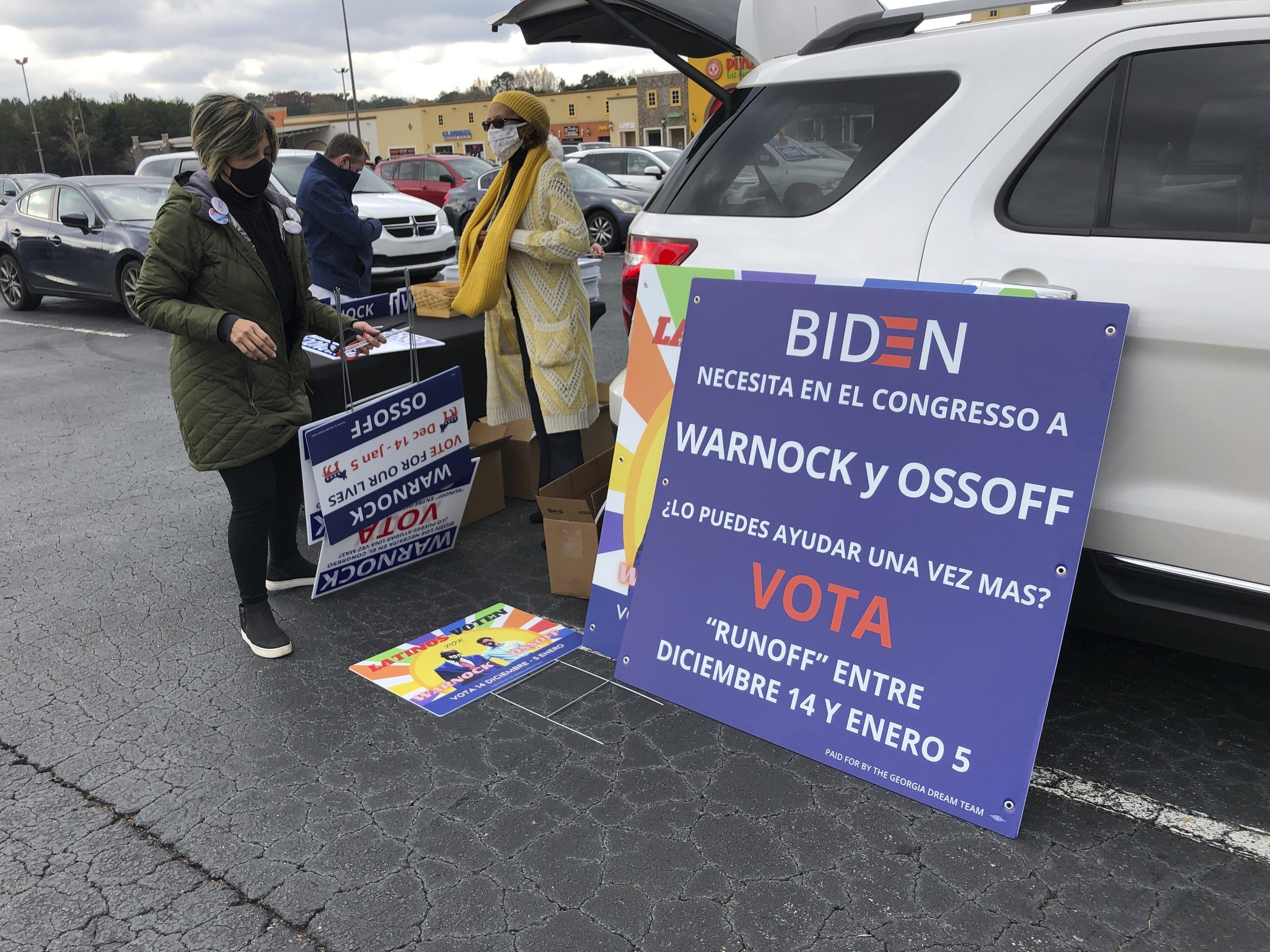 Volunteers assemble signs before a rally for Democratic U.S. Senate candidate Jon Ossoff and former U.S. Secretary of Housing and Urban Development Julian Castro in Lilburn, Ga., Monday, Dec. 7, 2020. The rally was part of an effort to register and mobilize voters in Georgia's growing Latino population for the two Democratic candidates in the Georgia's twin Jan. 5 Senate runoffs that will determine which party controls the U.S. Senate. (AP Photo/Jeff Amy)