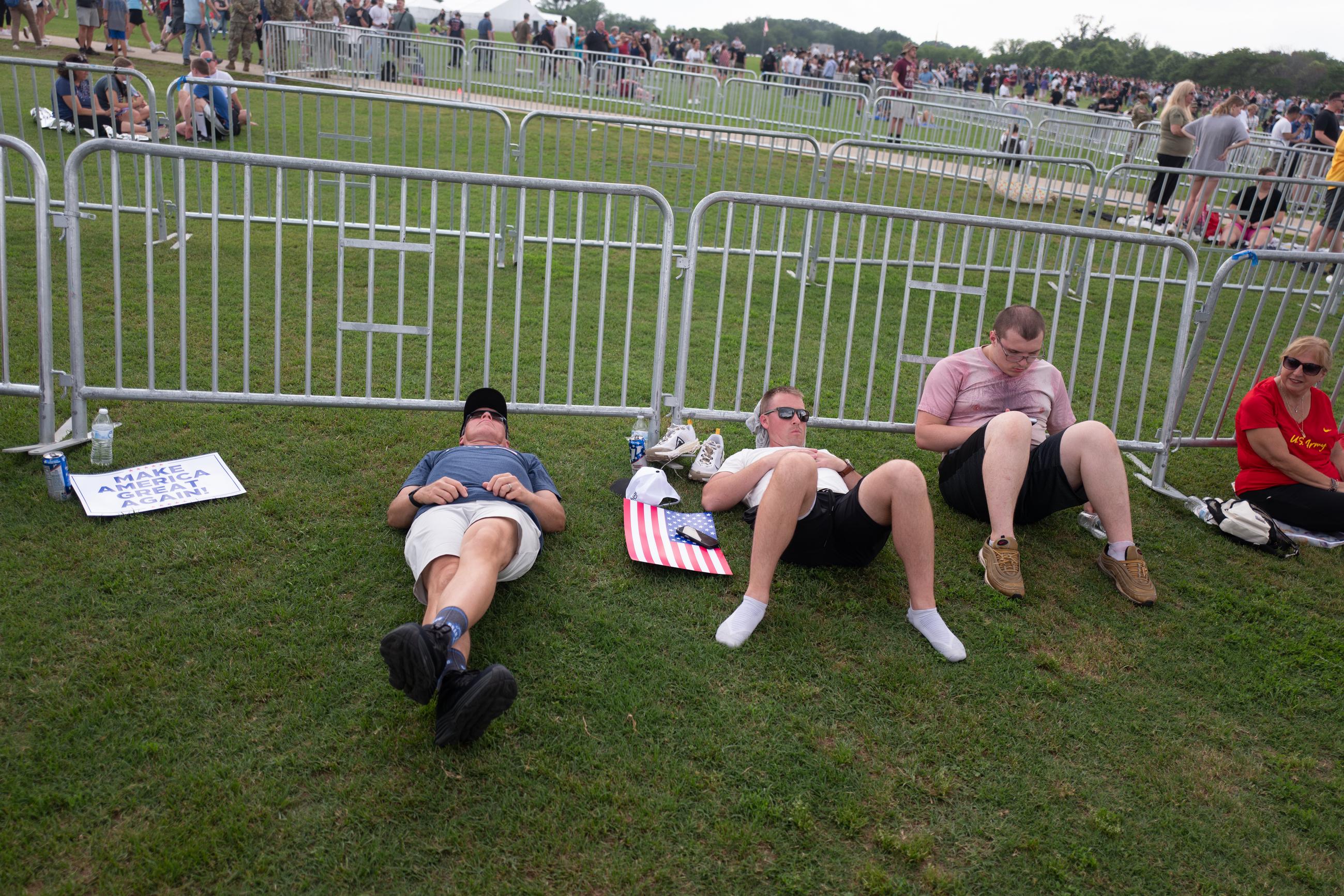 Attendees lay down along the barricade fence along the National Mall during the Army's 250th Birthday parade. June 15, 2025.