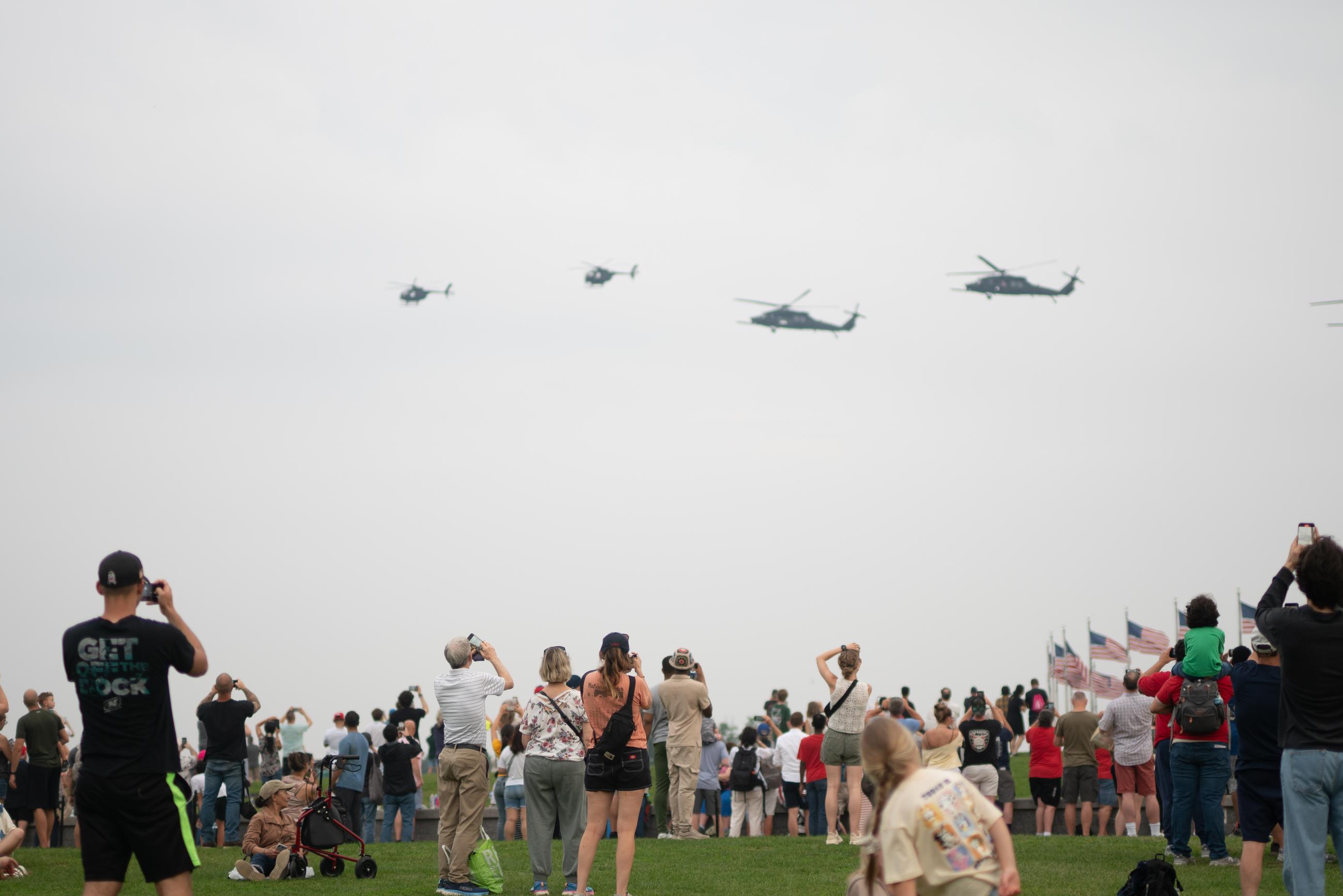 Attendees of the Army's 250th Birthday parade watch on as AH-64 Apache Helicopters fly over the National Mall. June 15, 2025.