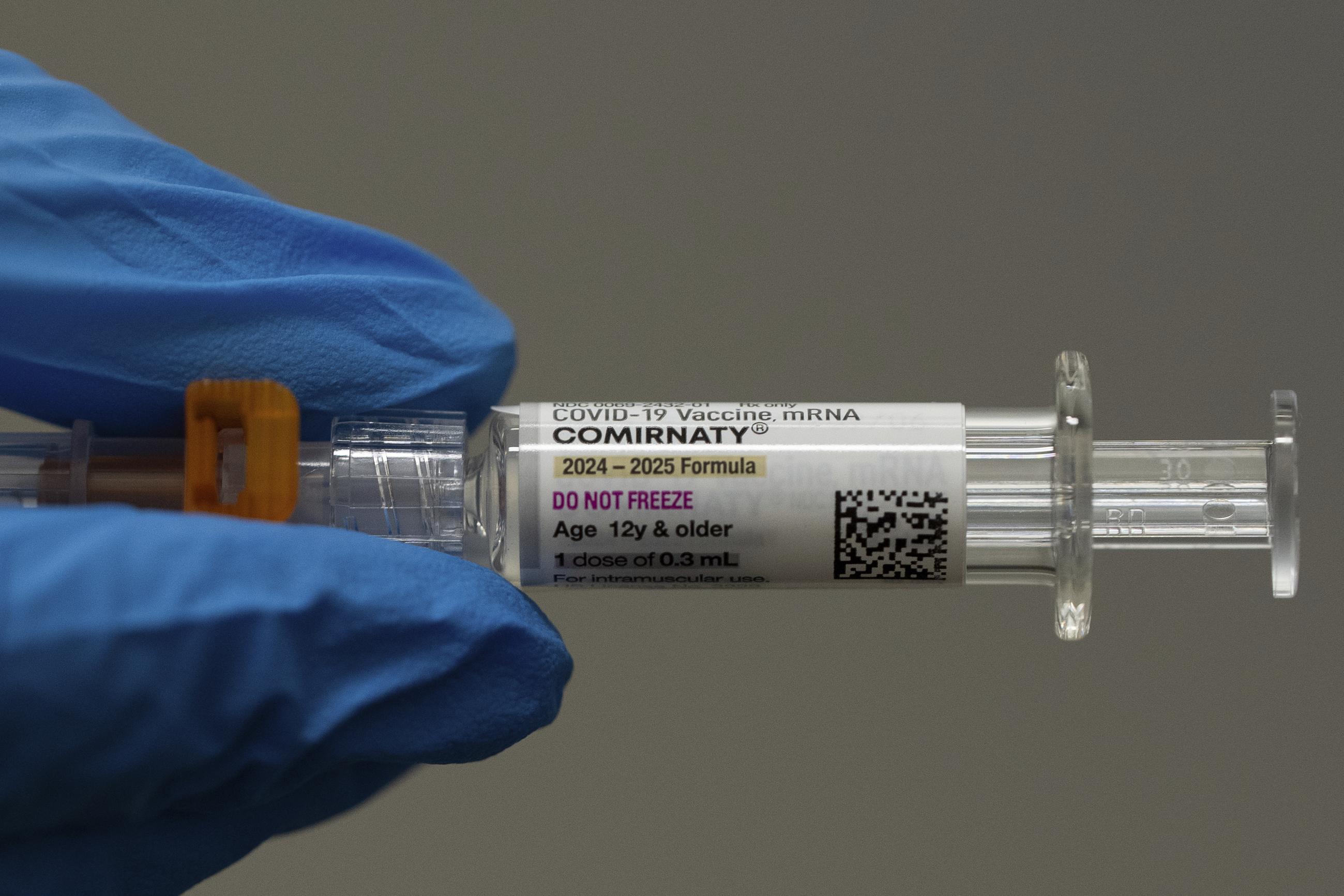 A pharmacist holds a Pfizer and BioNTech COVID-19 vaccine shot. (AP Photo/Jenny Kane)