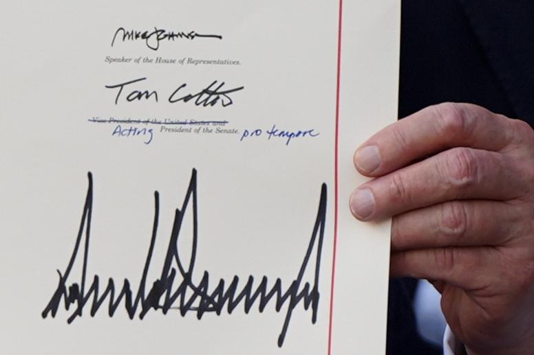 President Trump holds up the signed copy of his Big Beautiful Bill at the White House on July 4. (AP Photo/Julia Demaree Nikhinson)