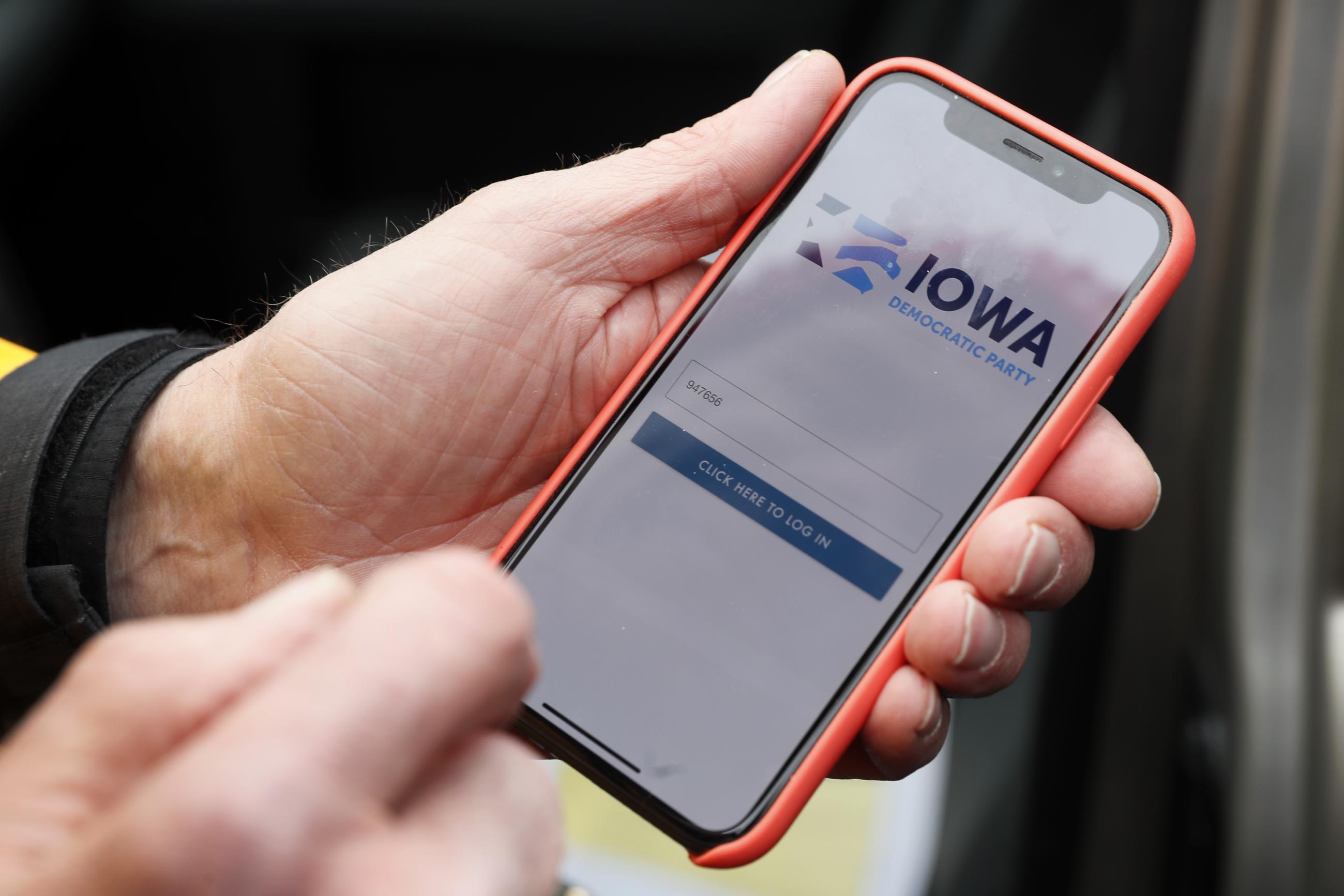 FILE - In this Nov. 15, 2019, file photo, a precinct captain from Des Moines holds his iPhone showing the Iowa Democratic Party’s caucus-reporting app, whose failure cast a cloud over the nominating process in that election. (AP PHOTO/CHARLIE NEIBERGALL)