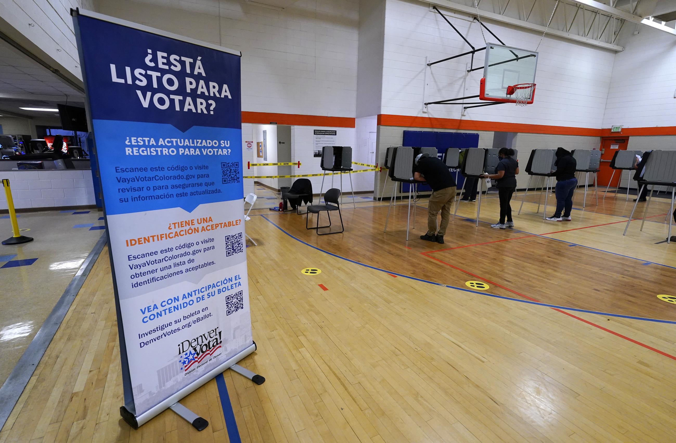 FILE - A sign in Spanish stands near voters as they cast their ballots at stations inside the La Familia Recreation Center in the Baker neighborhood Nov. 3, 2020, south of downtown Denver. This month’s elections may have offered a preview of the Spanish-language misinformation that could pose a growing threat to Democrats, who are already anxious about their standing with Latino voters after losing some ground with them last year. (AP Photo/David Zalubowski, File)