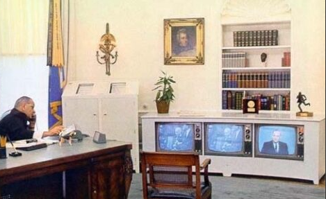 President Lyndon B. Johnson talking on the phone while watching three television sets in the Oval Office