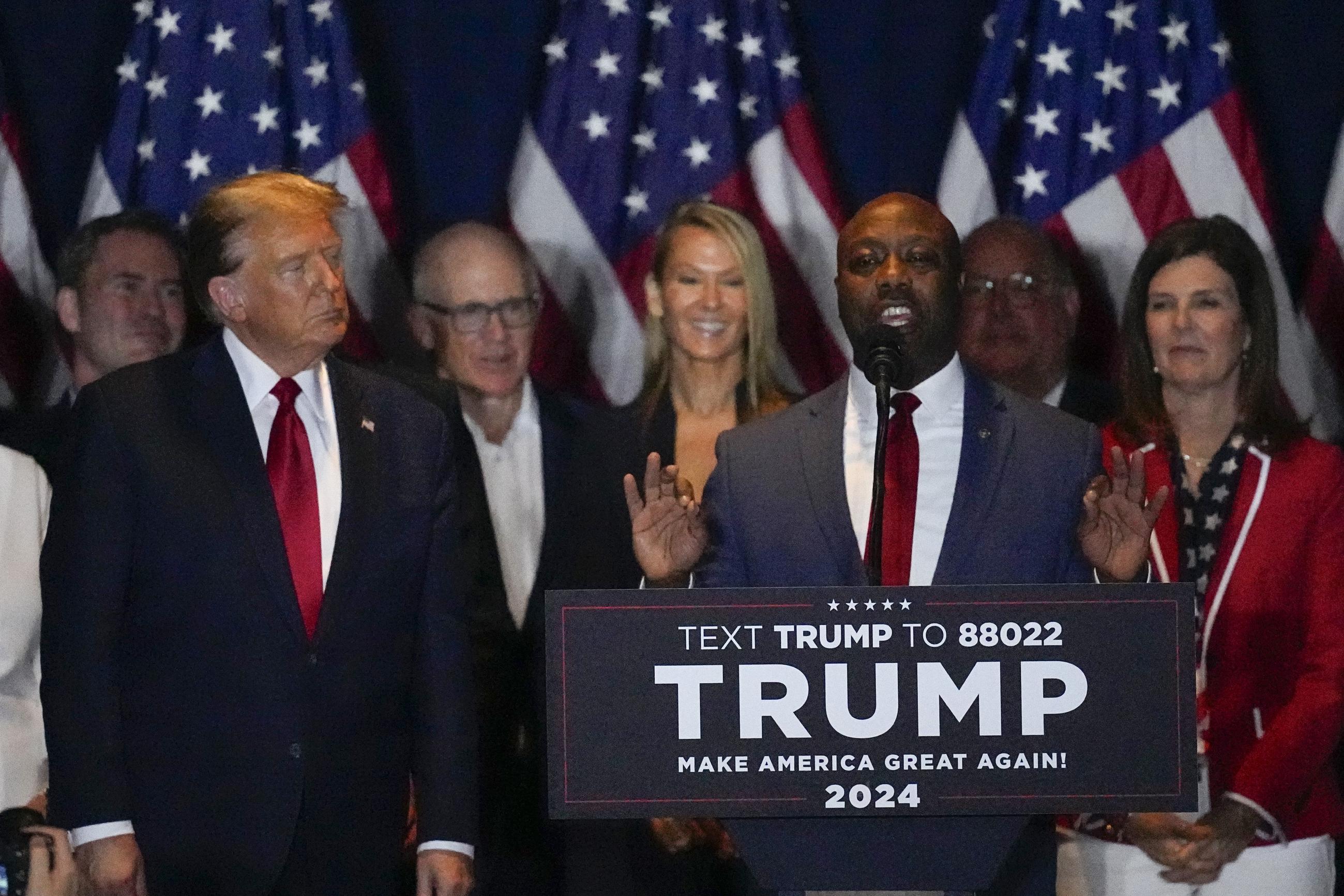 Donald Trump listens to Sen. Tim Scott at a primary night party in Columbia, S.C., on Feb. 24, 2024. (AP Photo/Mike Stewart)