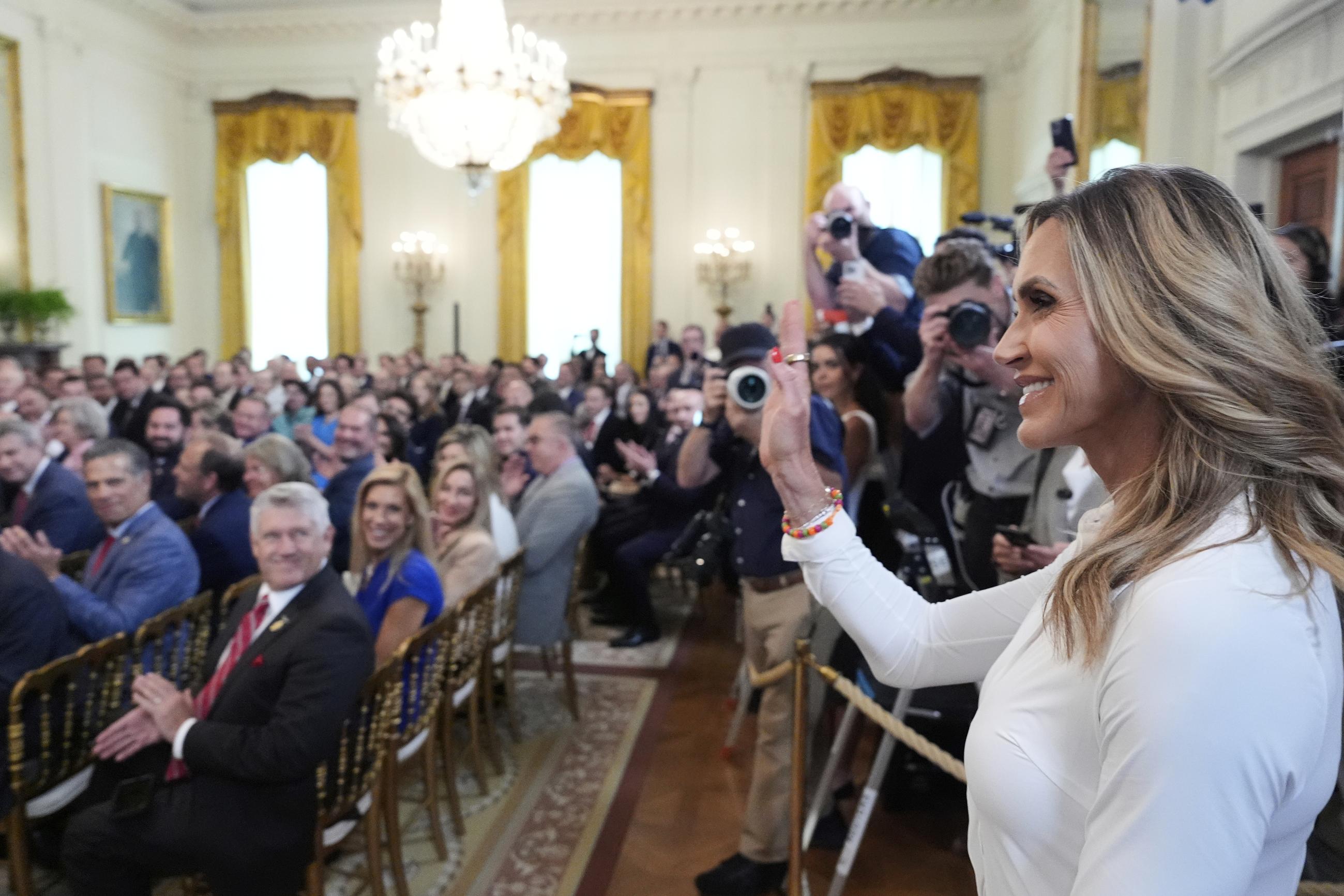 Lara Trump waves to the audience as President Donald Trump speaks at an event for the signing of the GENIUS Act, a bill that regulates stablecoins, a type of cryptocurrency, in the East Room of the White House, Friday, July 18, 2025, in Washington. (AP Photo/Alex Brandon)