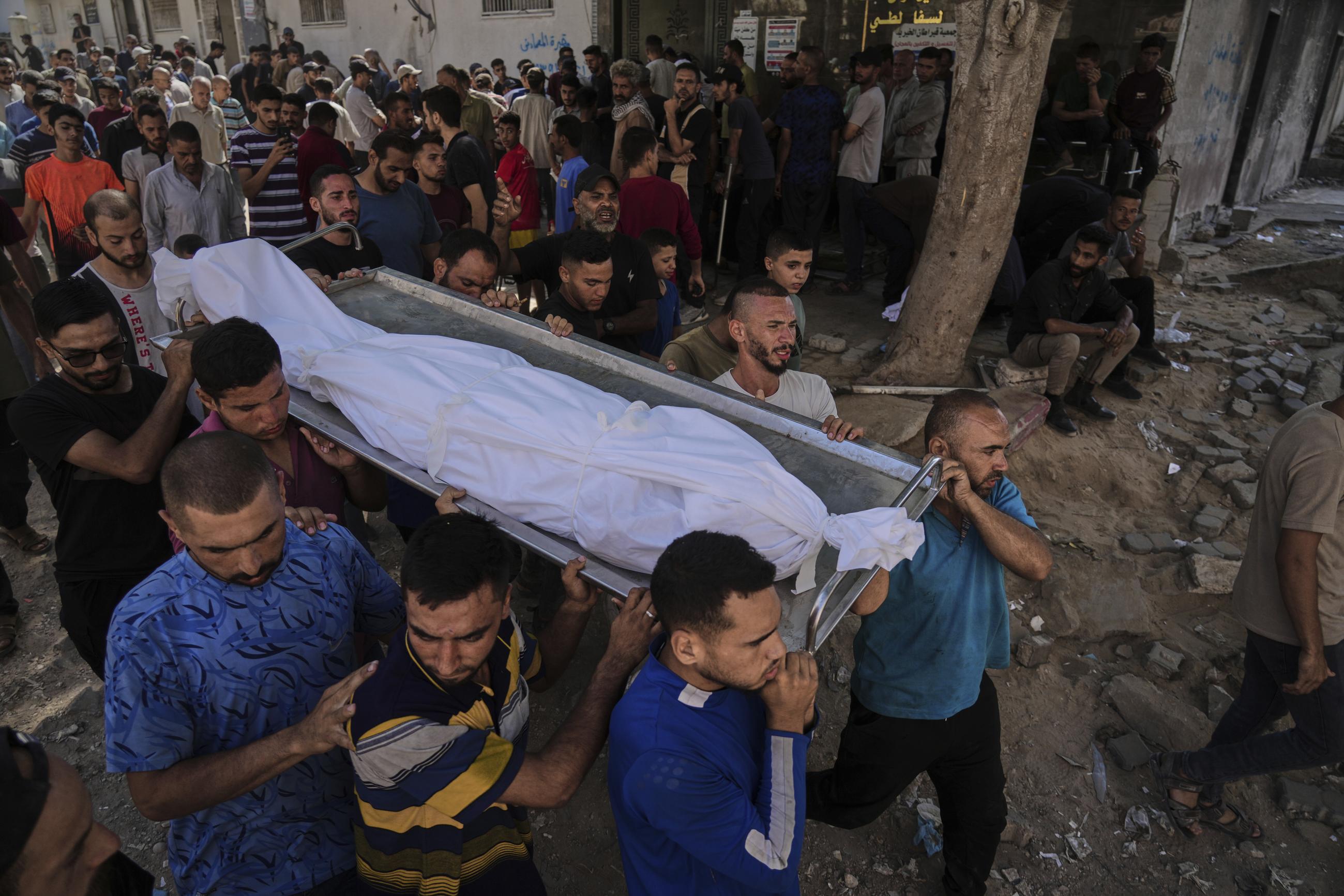 Palestinians carry the body of a person killed while trying to reach aid trucks in the Gaza Strip, Aug. 6, 2025. (AP Photo/Jehad Alshrafi)