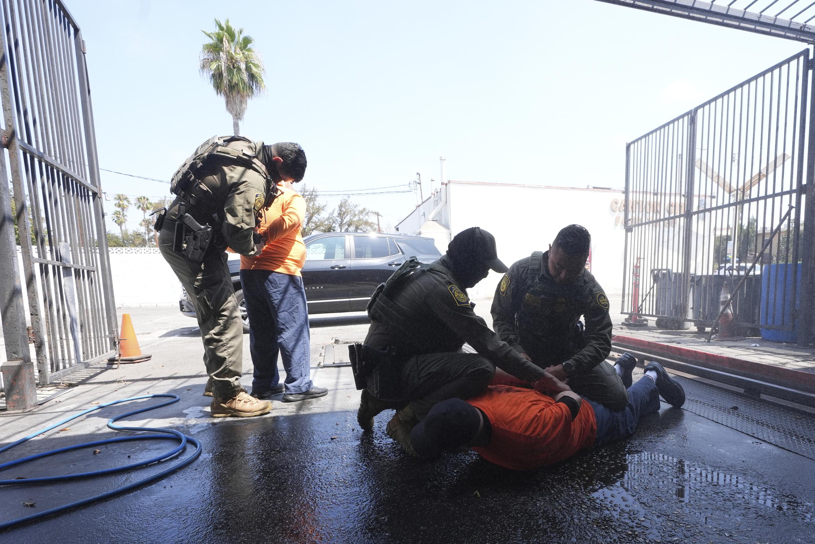 Immigration agents detain two men at a car wash in Montebello, Calif., on Aug. 15. (AP Photo/Gregory Bull)