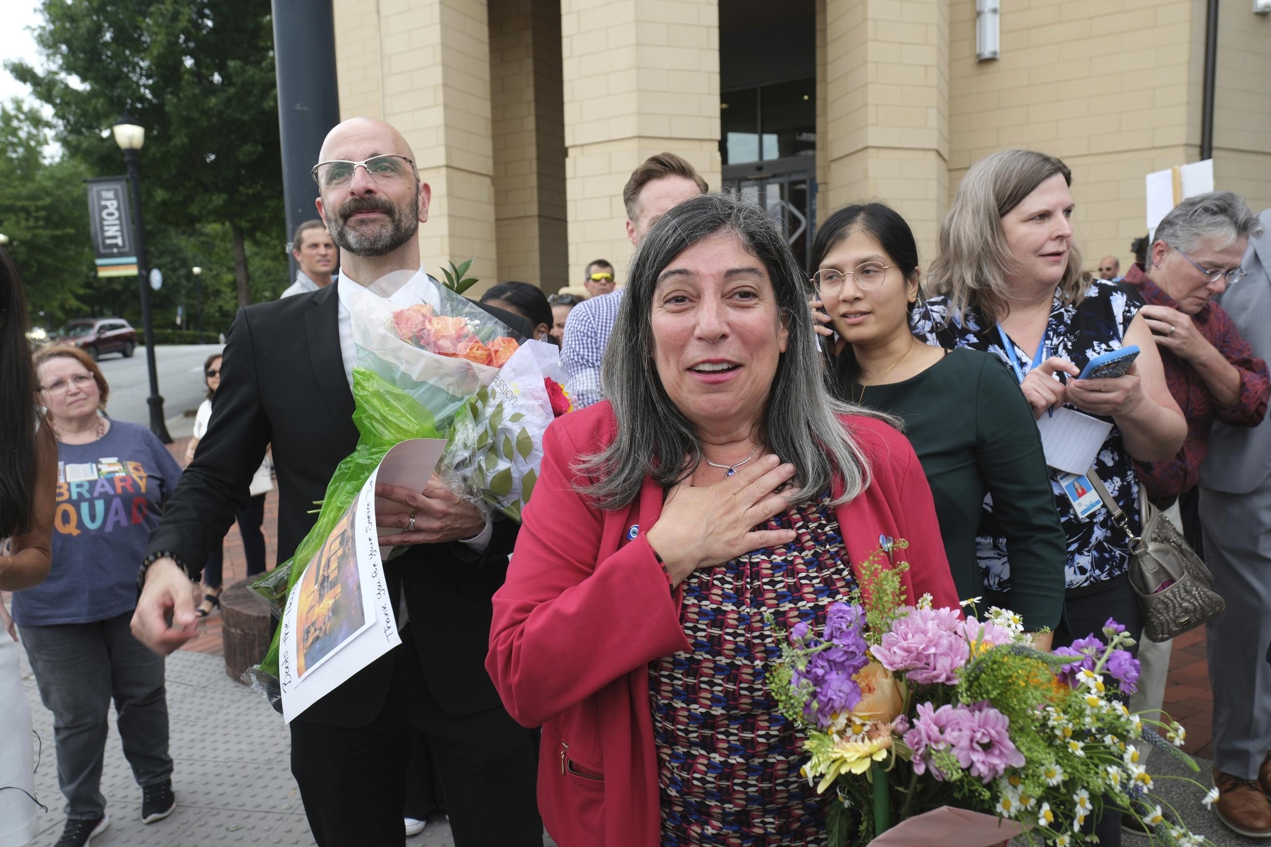 Demetre Daskalakis and Debra Houry are greeted by well-wishers outside CDC headquarters in Atlanta on Aug. 28. (AP Photo/Ben Gray)