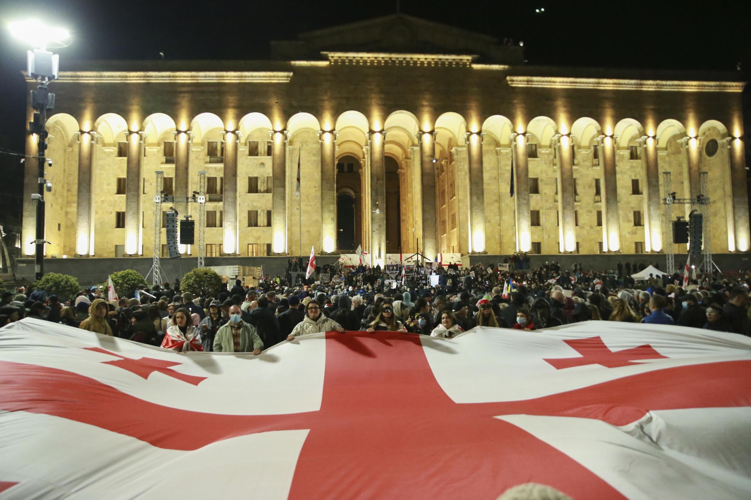 Demonstrators with a giant Georgian flag gather in front of the parliament to call for the release of political prisoners and demand new elections on March 31. (AP Photo/Zurab Tsertsvadze)
