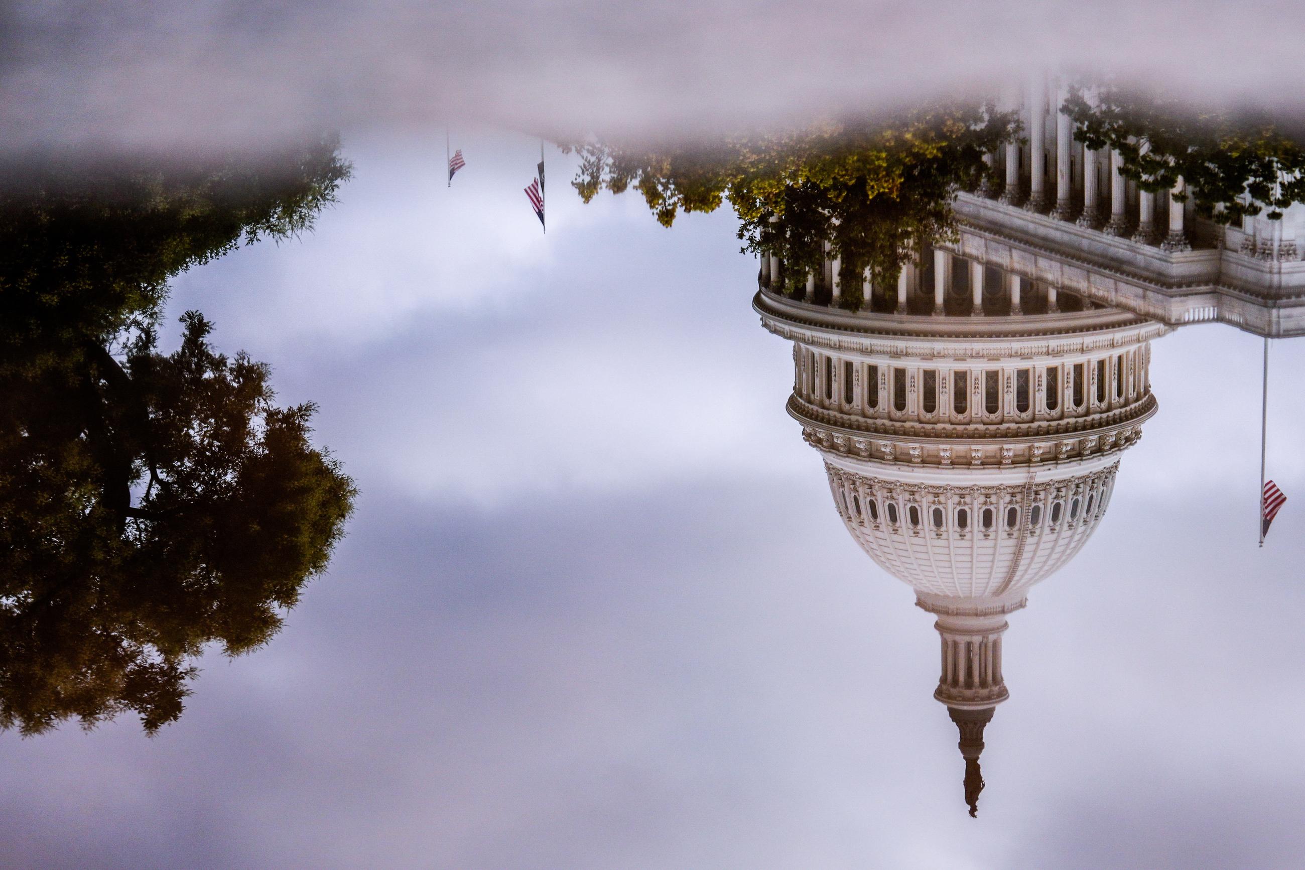 The U.S. Capitol is reflected in a puddle outside of the Rayburn House Office Building in July. (AP Photo/Julia Demaree Nikhinson)
