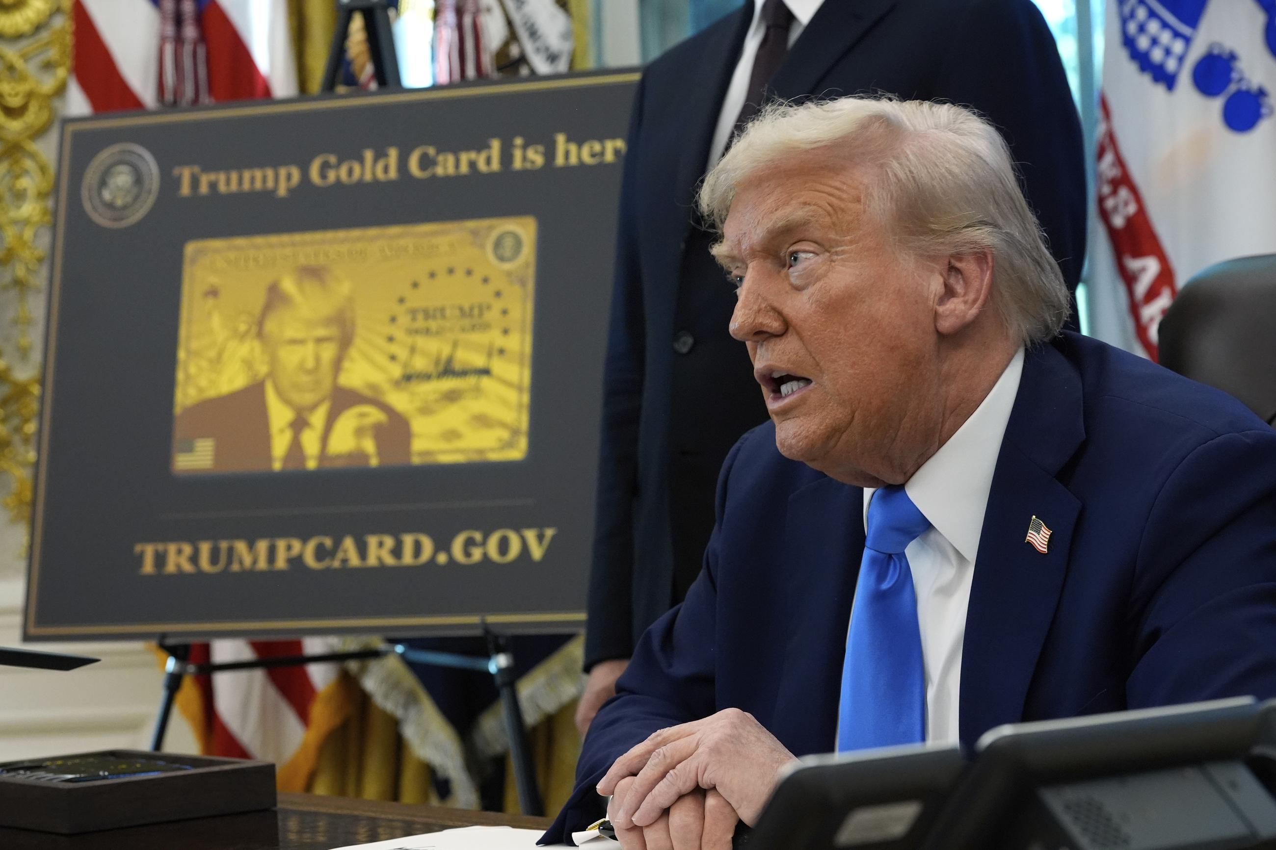 A poster showing the Trump Gold Card is seen as President Trump signs executive orders in the Oval Office, Sept. 19, 2025. (AP Photo/Alex Brandon)