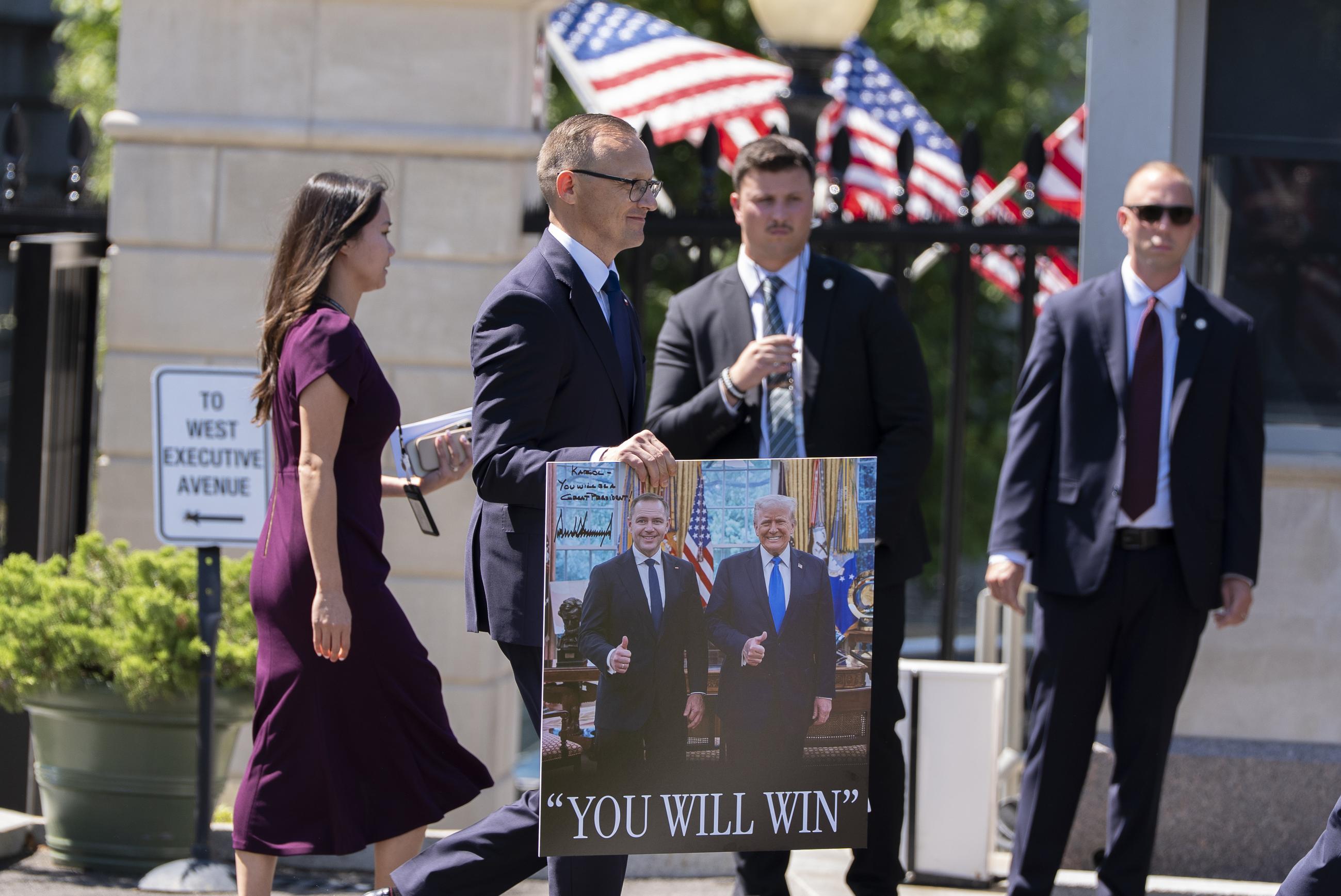 A signed photograph of Polish President Karol Nawrocki and President Trump is carried out of the White House on Sept. 3. (AP Photo/Alex Brandon)