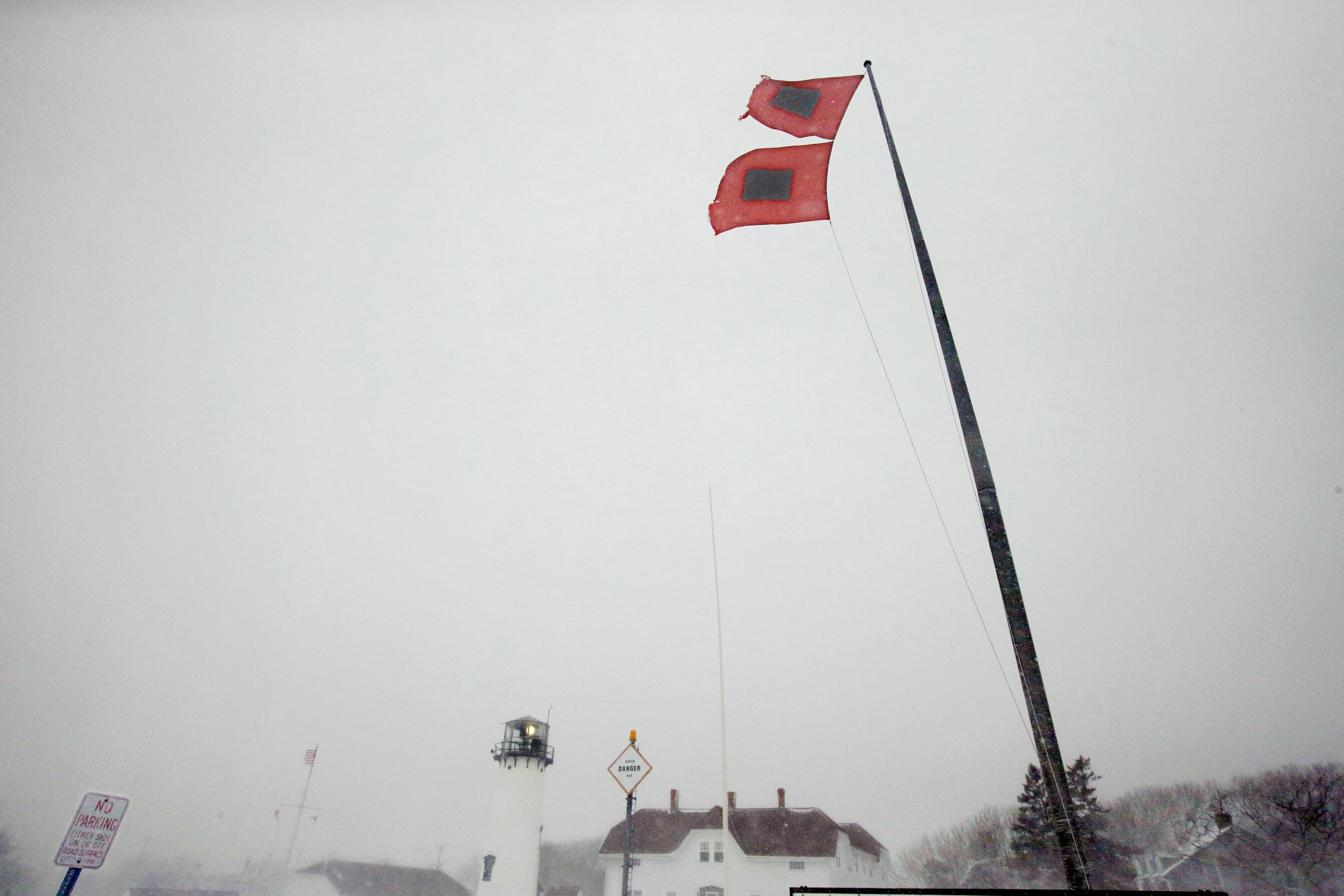 Hurricane flags fly over U.S. Coast Guard Lifeboat Station Chatham and Chatham Light, in Chatham, Mass., March 26, 2014. (AP Photo/Stephan Savoia)