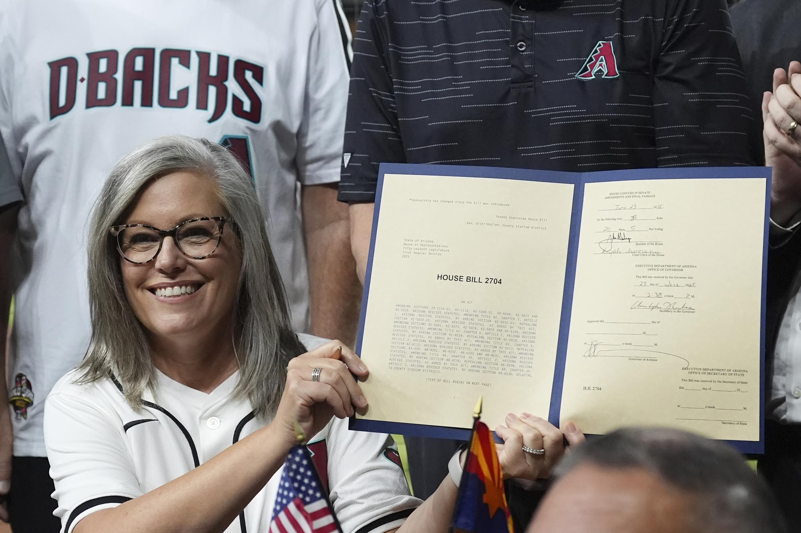 Arizona Democratic Gov. Katie Hobbs holds up the signed HB2704 for Chase Field stadium funding during a ceremonial event prior to a baseball game between the Arizona Diamondbacks and the Texas Rangers Wednesday, Sept. 3, 2025, in Phoenix. (AP Photo/Ross D. Franklin)