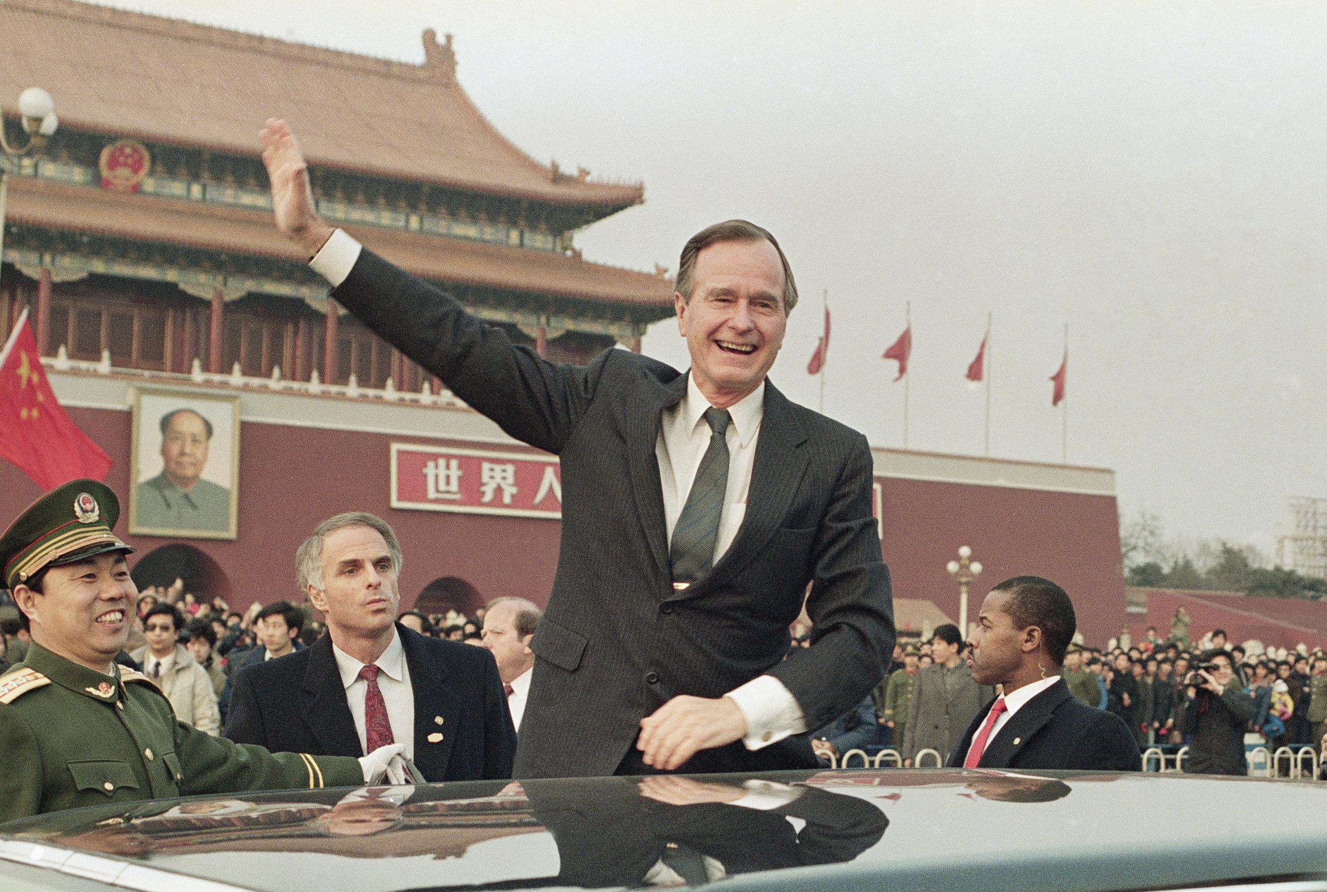 In this Feb. 25, 1989, file photo, President George H.W. Bush stands on his car and waves to the crowds in Tiananmen Square in Beijing. (AP Photo/Doug Mills, File)