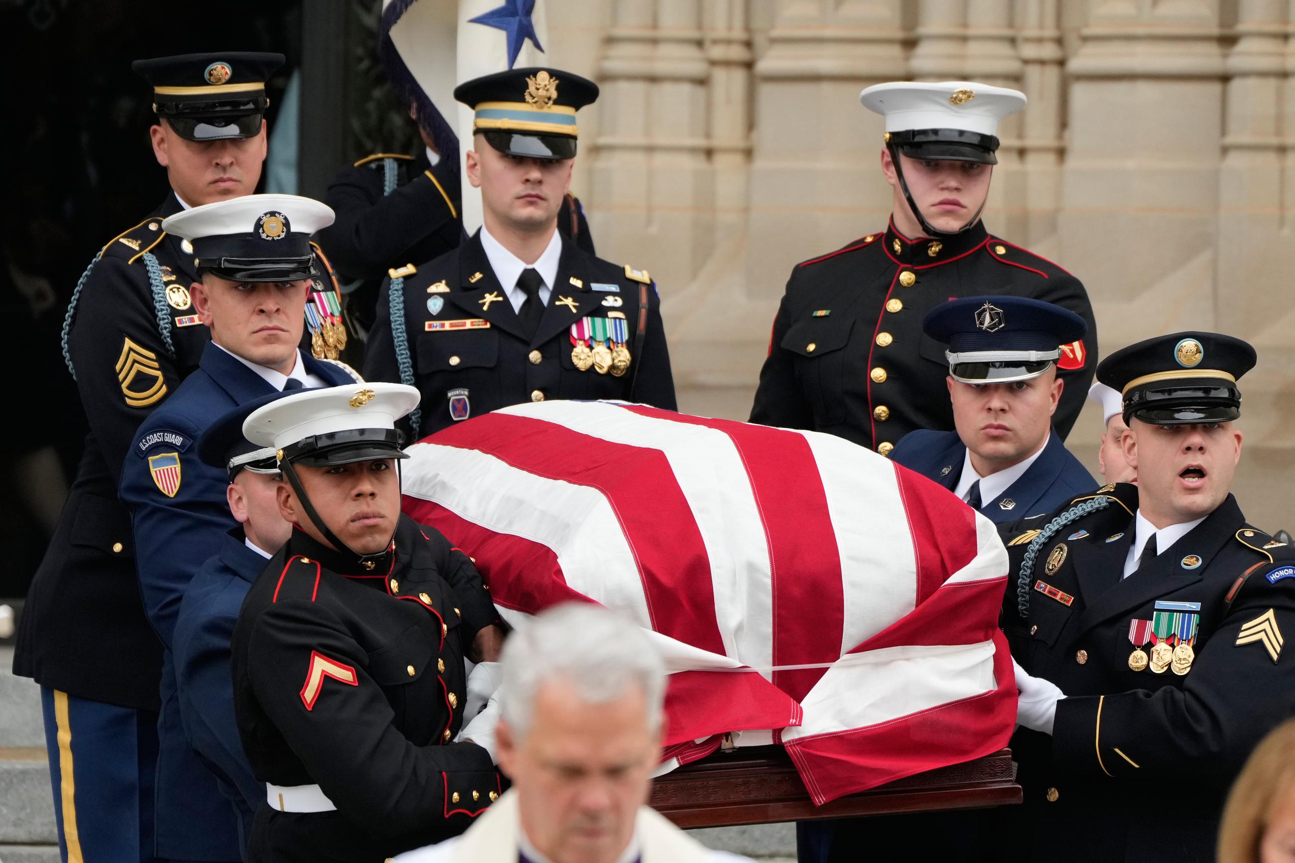 A joint services body-bearer team carries the flag-draped casket out of the Cathedral. (AP Photo/Mark Schiefelbein)