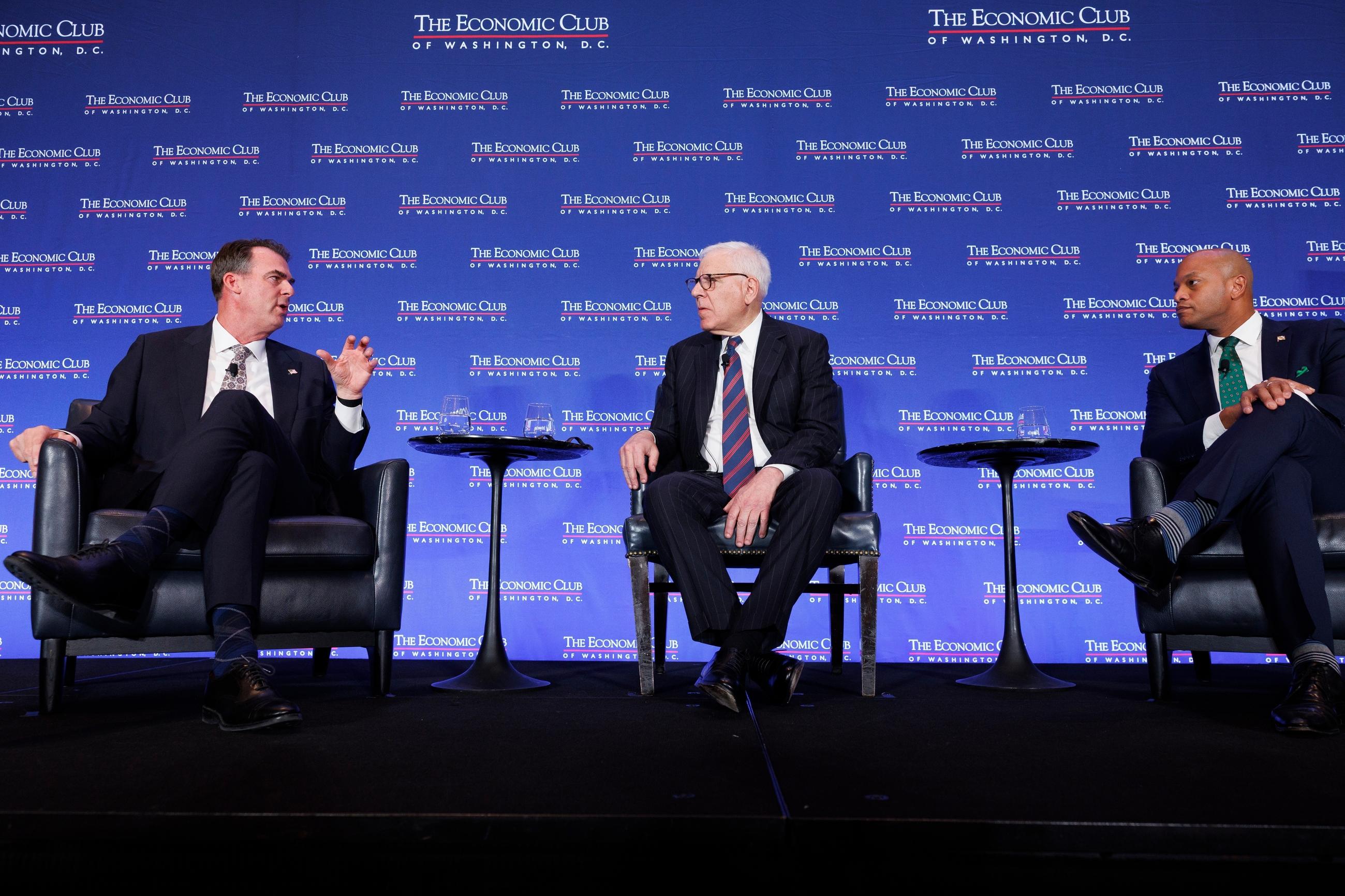 Gov. Kevin Stitt, R-Okla., chair of the National Governors Association (NGA), from left, Economic Club of Washington Chairman David Rubenstein, and Gov. Wes Moore, D-Md., vice chair of the NGA participate in a panel discussion during a conference at the Economic Club of Washington Wednesday, Feb. 18, 2026, in Washington. (AP Photo/Tom Brenner)