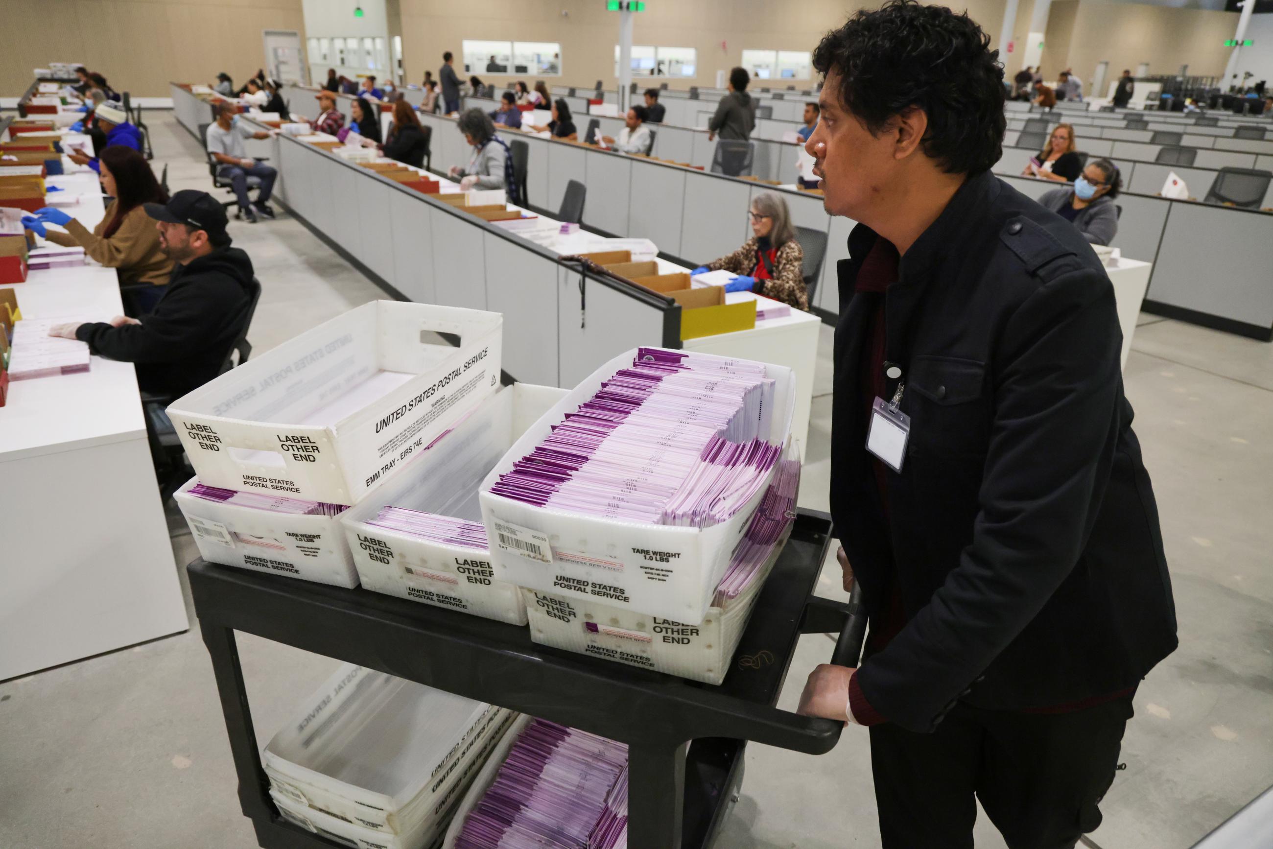A worker pushes a cart of received mail ballots at the LA County Ballot Processing Center in City of Industry, Calif., on Nov. 4, 2025. (AP Photo/Ethan Swope, File)