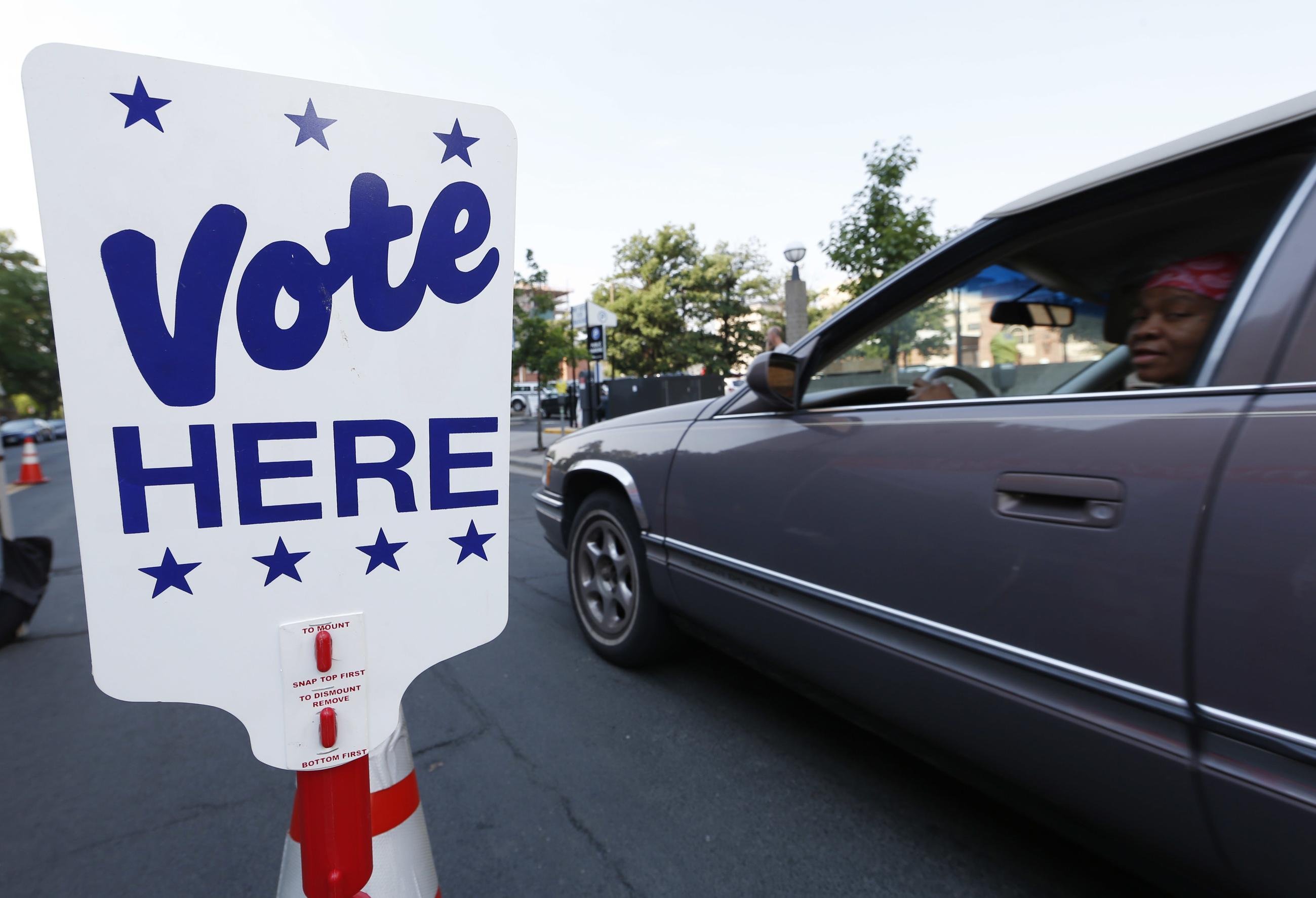 A motorist pulls up to hand off her ballot as voters drop off their ballots in the primary election at a drive-in site outside the city's election commission headquarters Tuesday, June 28, 2016, in Denver. (AP Photo/David Zalubowski)