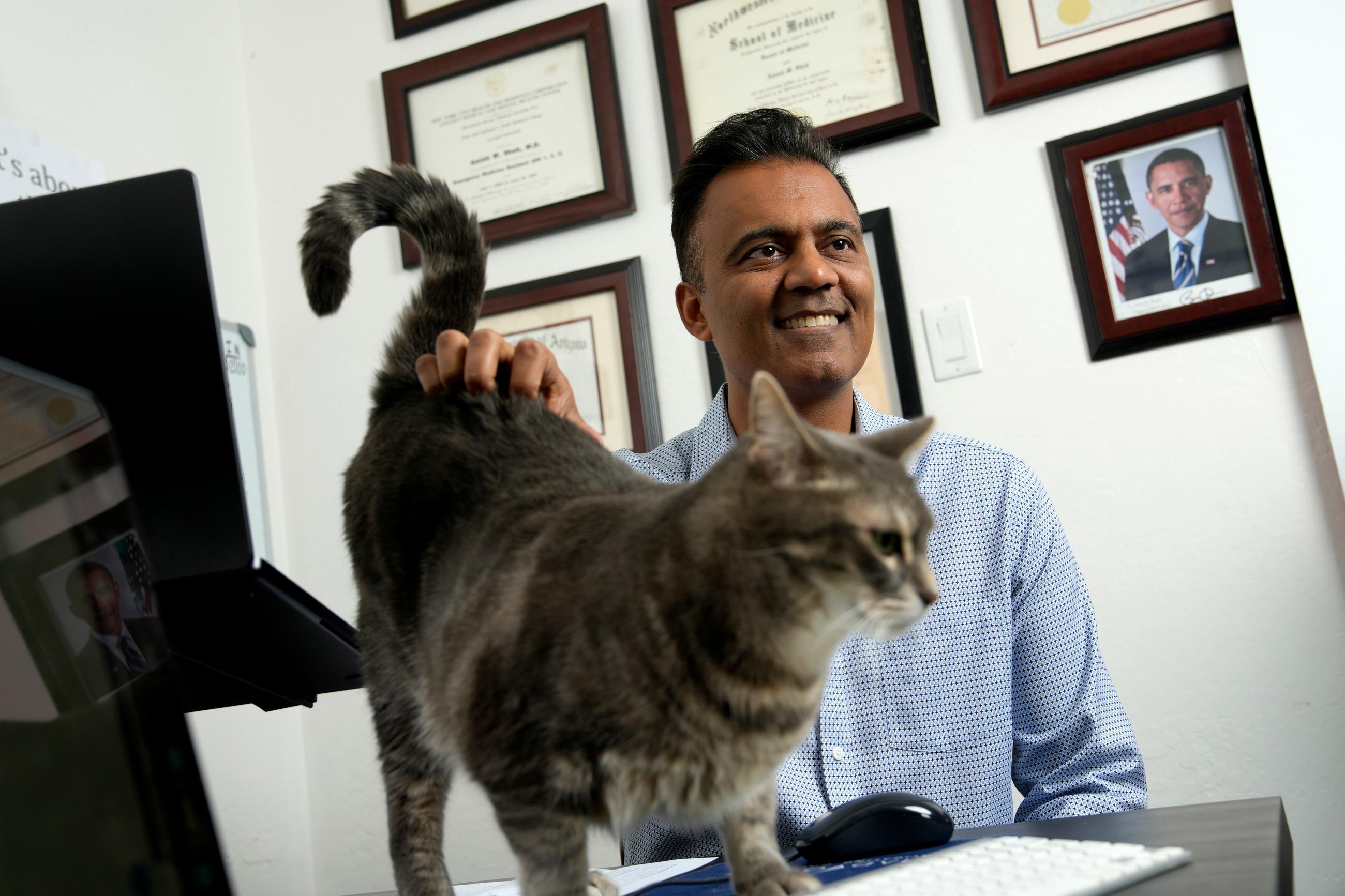 Democratic candidate for Arizona's 1st Congressional Dr. Amish Shah pauses a strategy talk with a staffer as he pets one of his cats, Thursday, July 16, 2026, in Phoenix. (AP Photo/Ross D. Franklin)