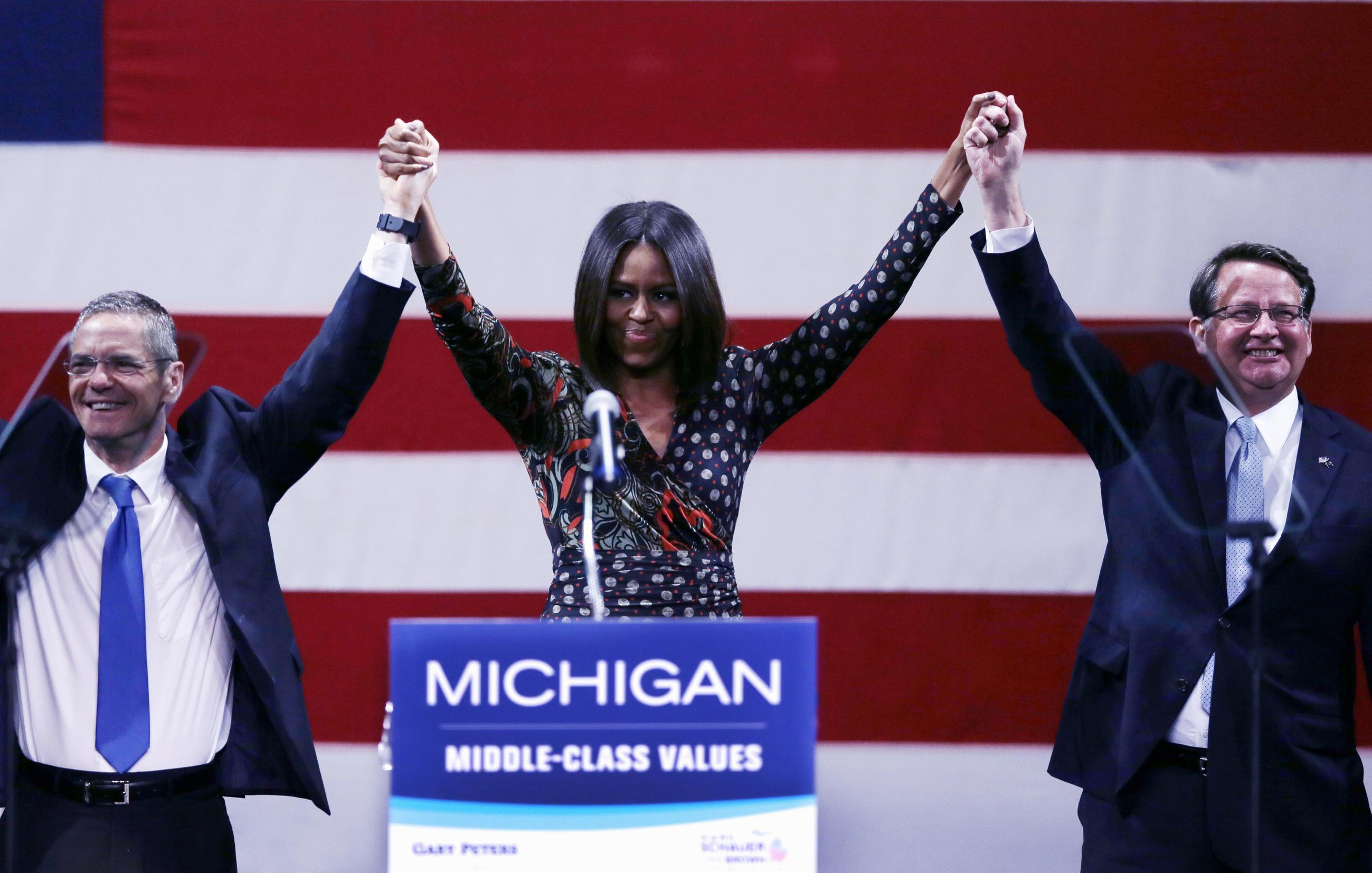 First lady Michelle Obama stands with Michigan gubernatorial candidate Mark Schauer, left, and Senate candidate, Rep. Gary Peters during a campaign rally for them in Detroit, Friday, Oct. 10, 2014. Michelle Obama came to heavily Democratic Detroit Friday afternoon to rally support for Peters, a suburban Detroit congressman hoping to succeed retiring Democrat Sen. Carl Levin after 36 years in office. (AP Photo/Carlos Osorio)
