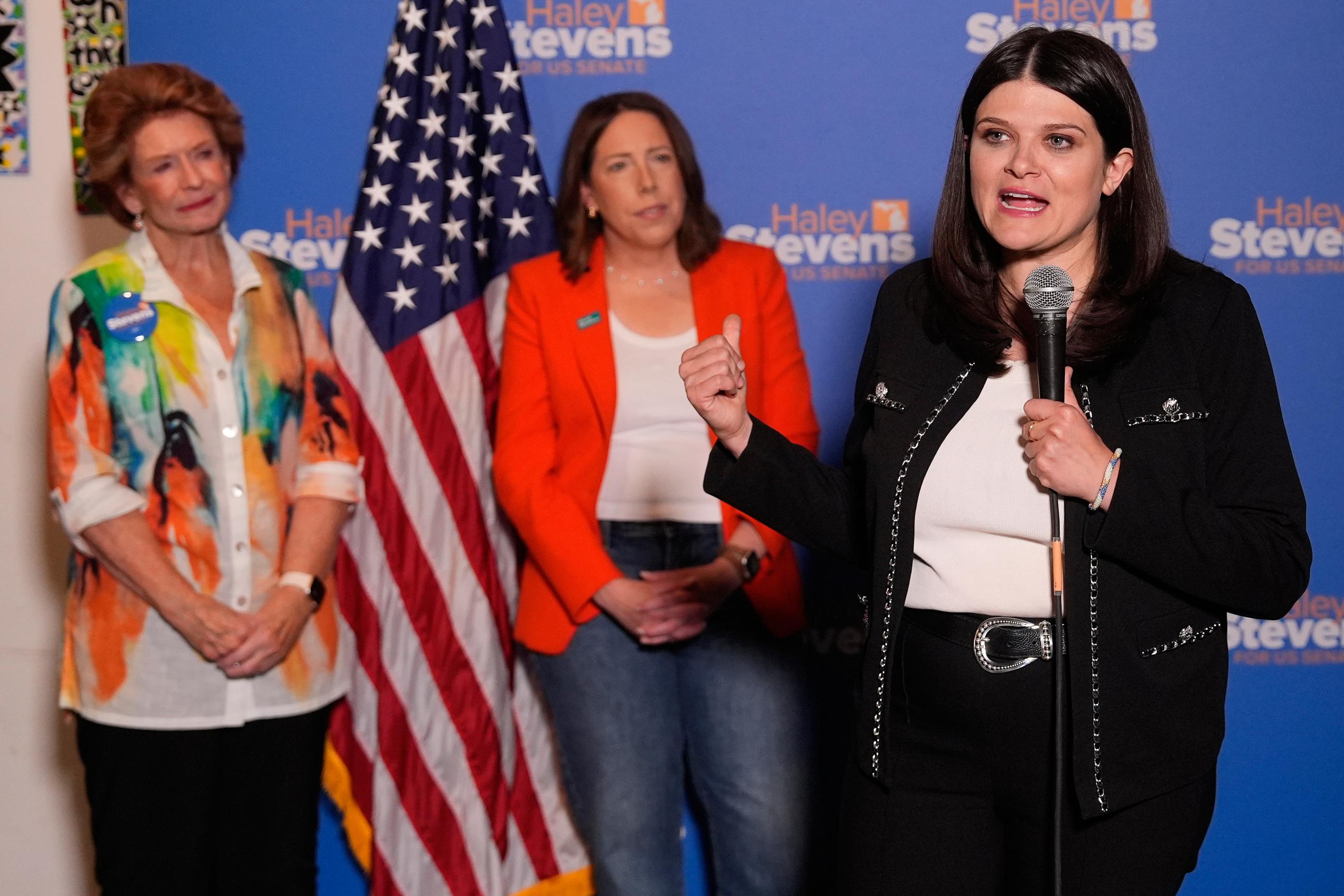 Rep. Haley Stevens, right, a candidate in the Democratic primary for U.S. Senate in Michigan, speaks during a campaign event, Monday, Aug. 3, 2026, in Grand Rapids, Mich., as former Sen. Debbie Stabenow and EMILYs List President Jessica Mackler listen. (AP Photo/Paul Sancya)