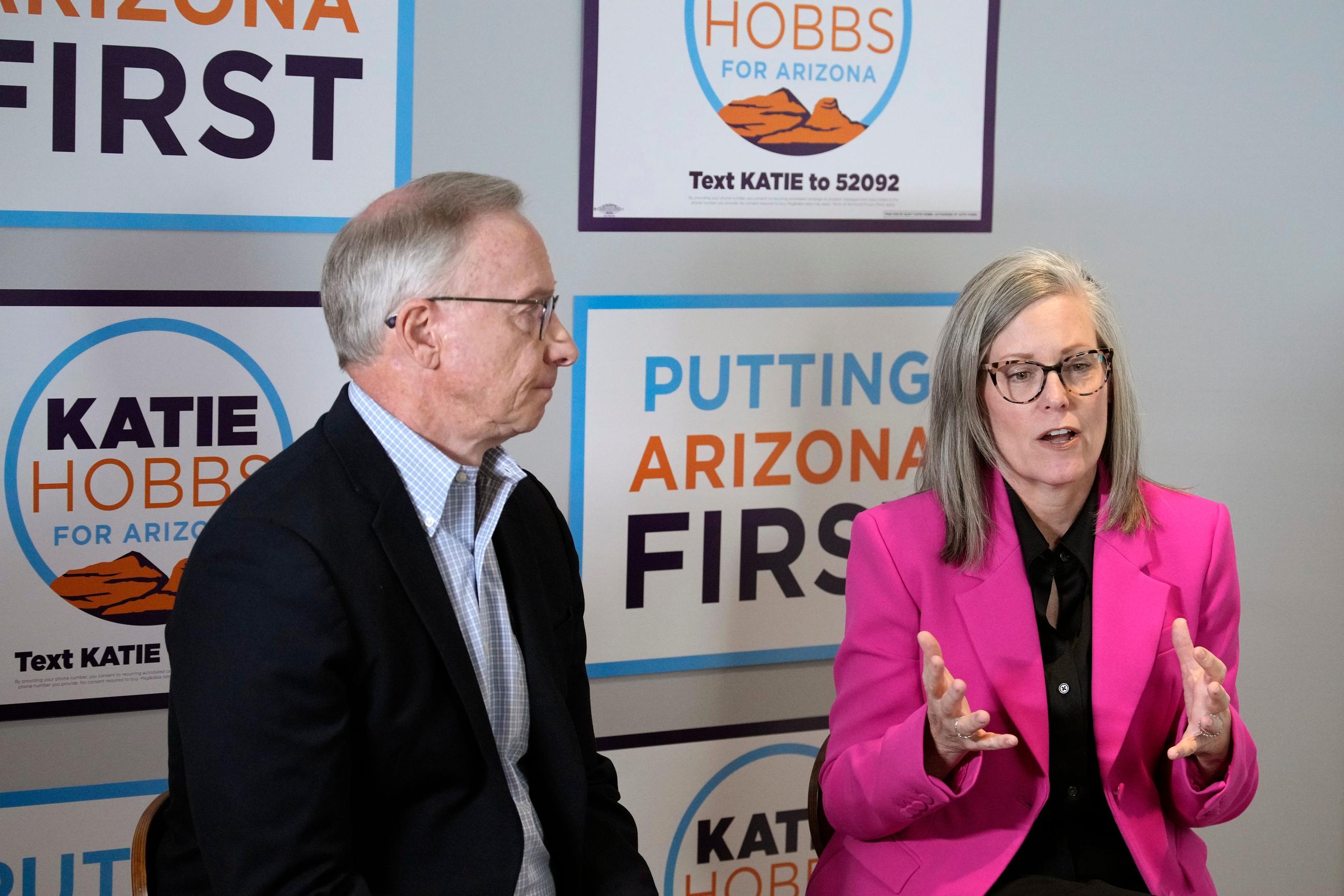 Arizona Democratic Gov. Katie Hobbs, right, sits down with her running mate for Lieutenant Governor John Giles, the former Republican Mesa, Ariz., mayor, Monday, Aug. 10, 2026, in Phoenix. (AP Photo/Ross D. Franklin)