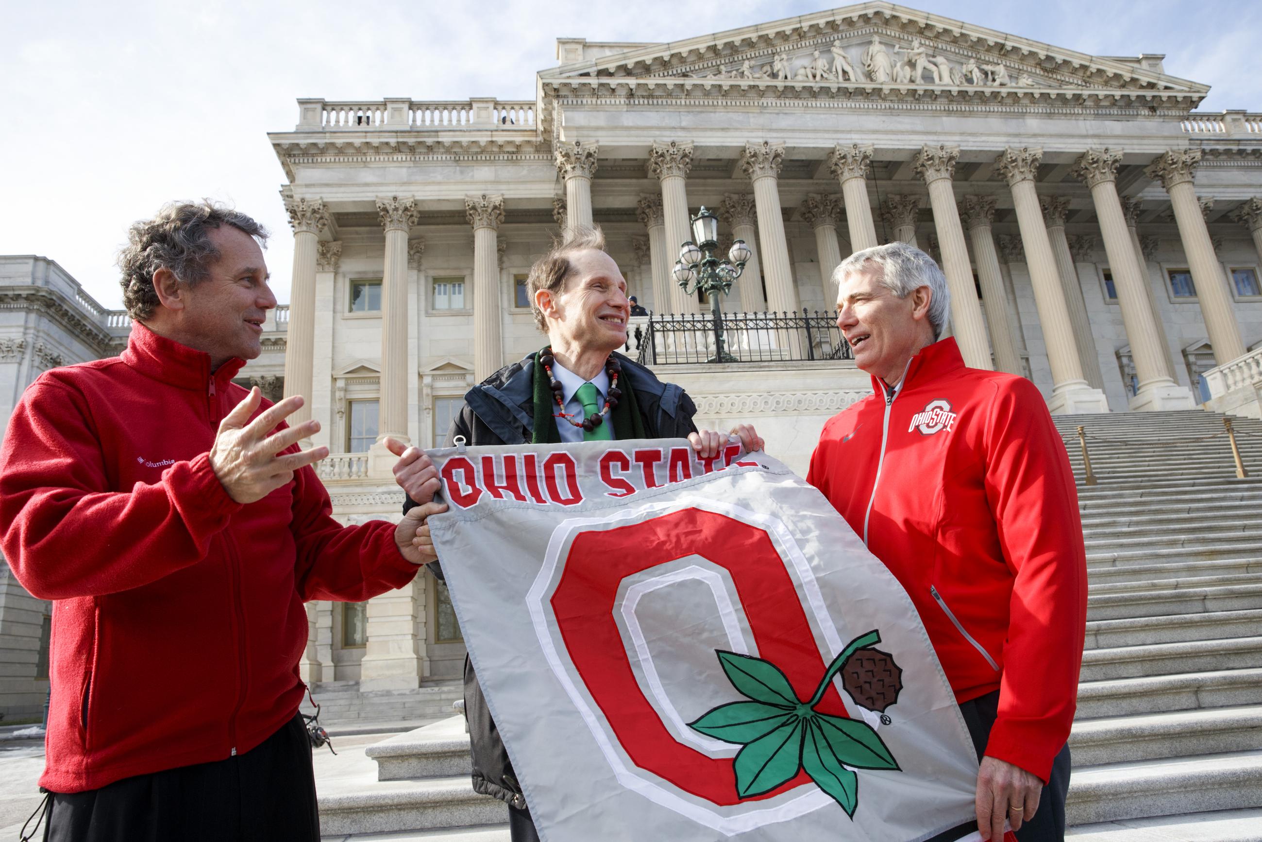 Sens. Sherrod Brown (left) and Rob Portman (right) of Ohio have some fun with Sen. Ron Wyden of Oregon (center) on the steps of the Senate on the day after Ohio State University defeated the University of Oregon in the inaugural college football playoff final in 2015. (AP Photo/J. Scott Applewhite)